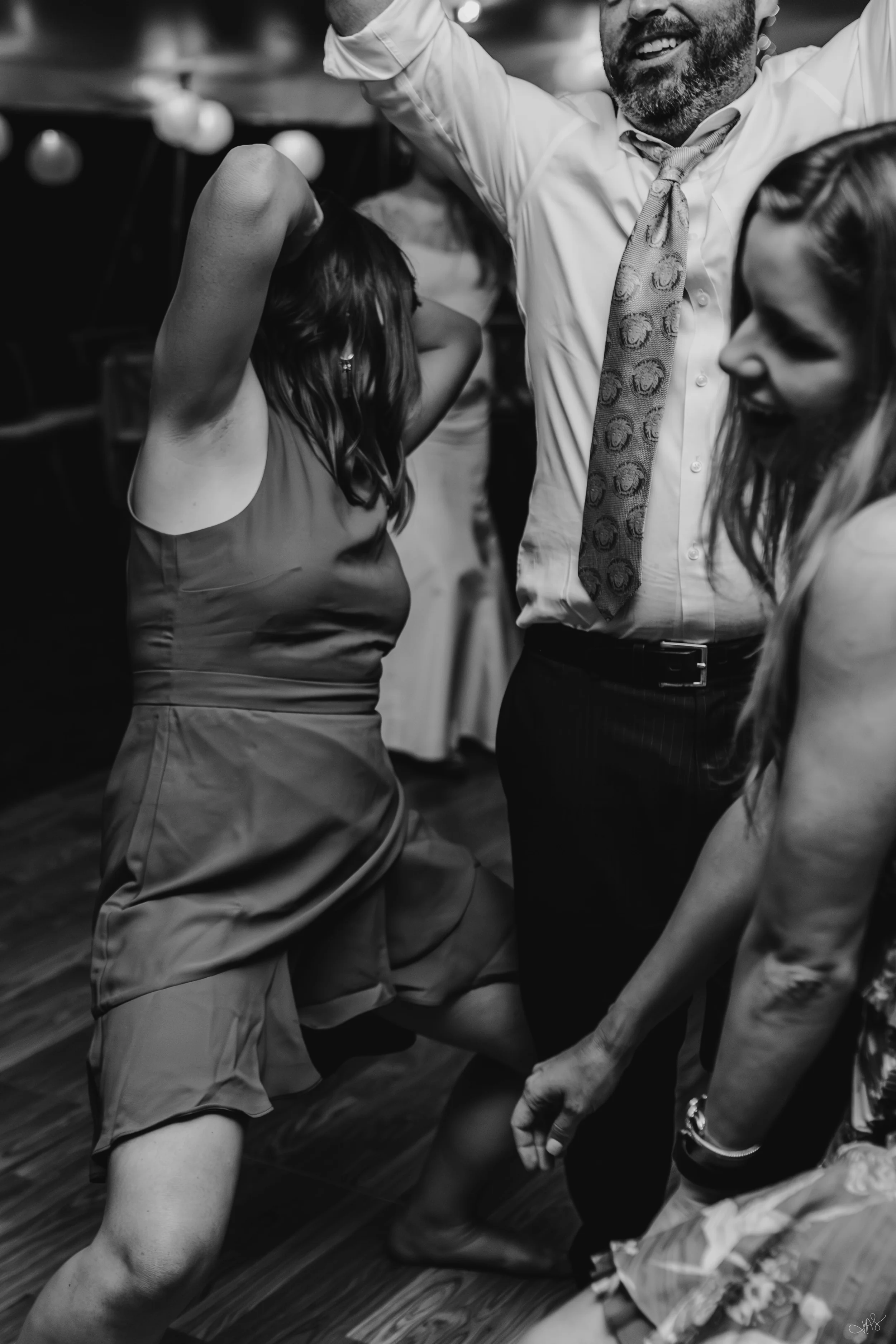 People dancing closely together in a lively setting, with some visible smiles and energetic body language, in a black and white photo.