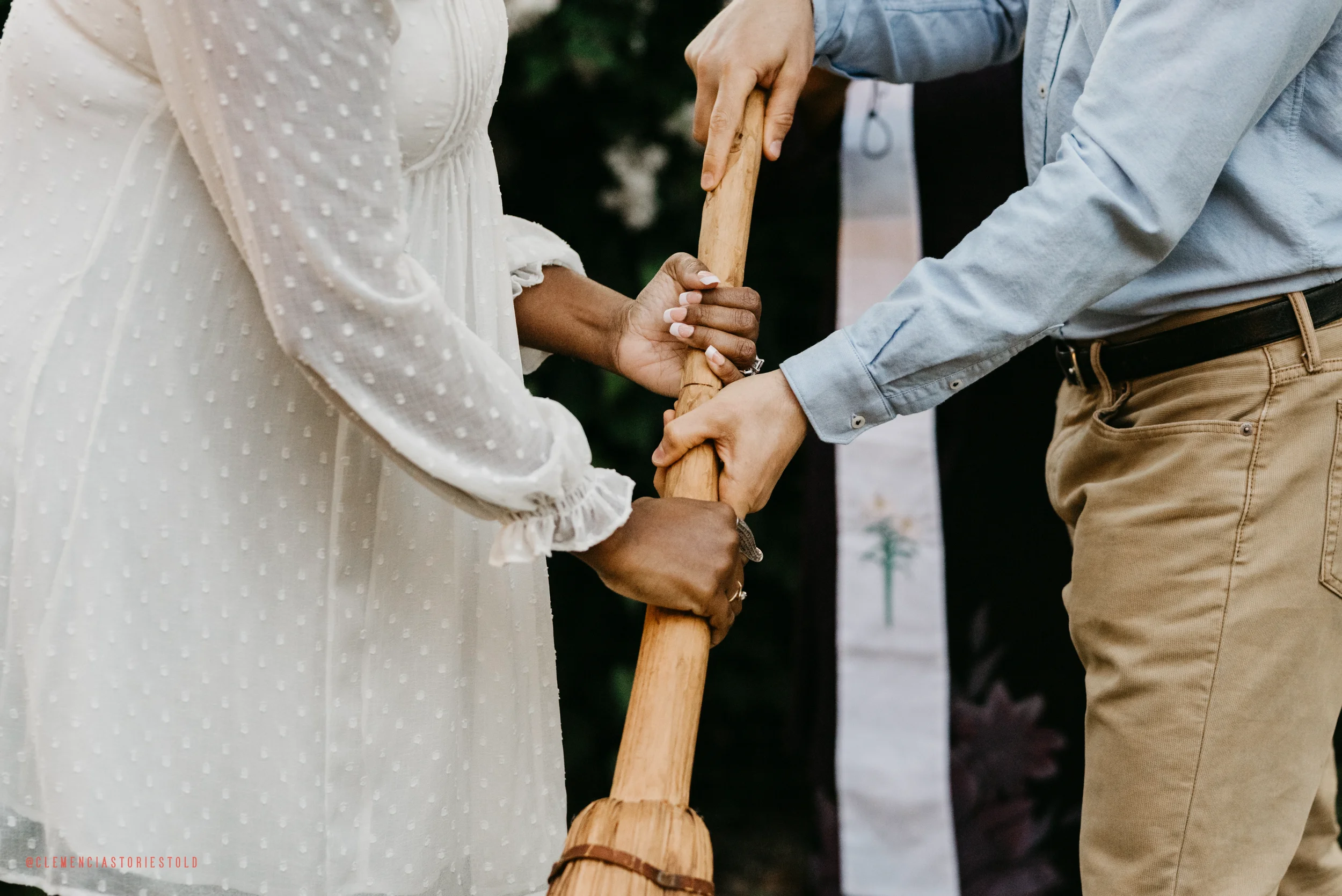 A couple holding a wooden staff during their wedding ceremony.