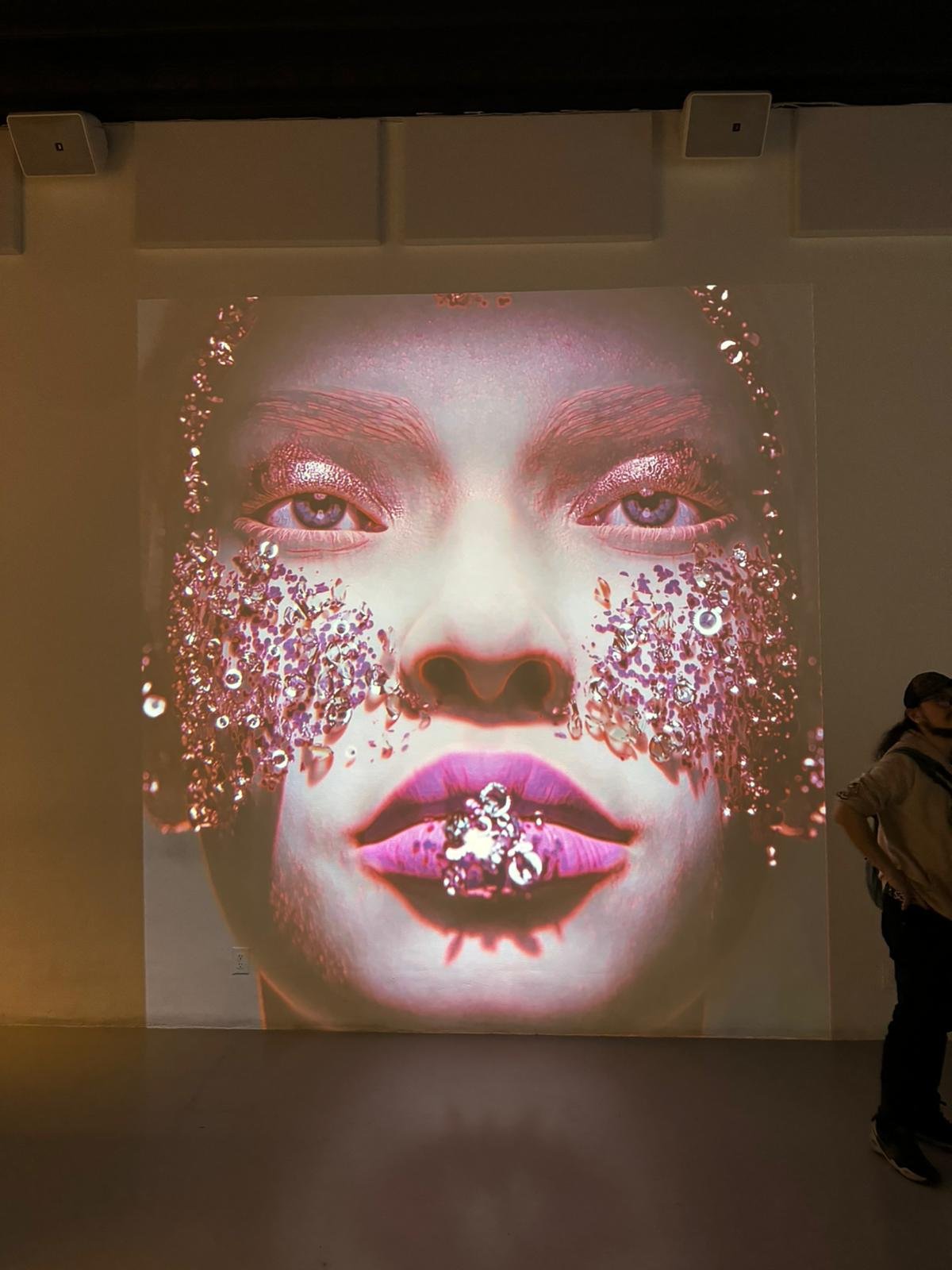‘The Shimmering Veil’ by Shavonne Wong, a large-scale digital portrait projection featuring glittering textures and surreal beauty, exhibited at Lume Studios in New York City.