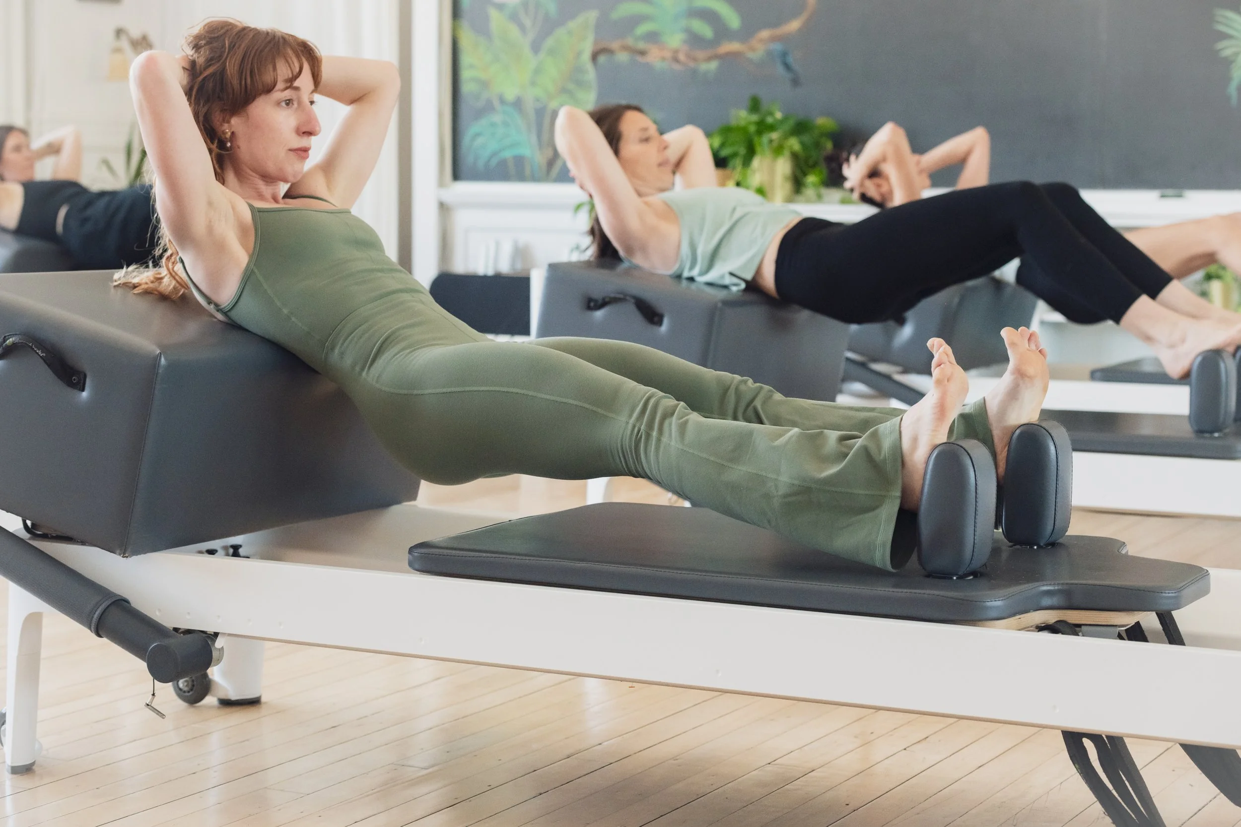 A woman practices reformer pilates at Muse along with friends