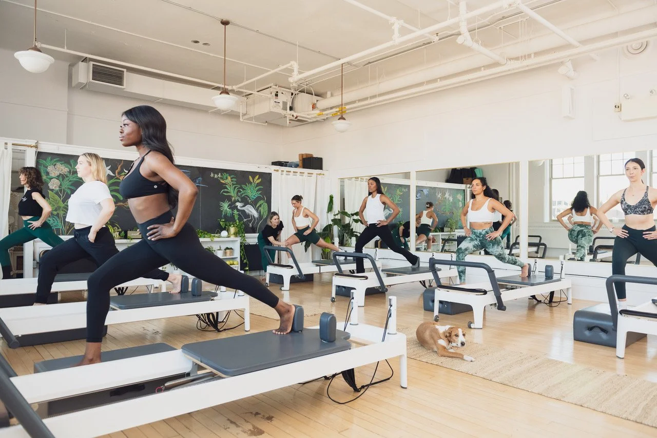 Students practicing balance on pilates reformers at Muse Movement studio