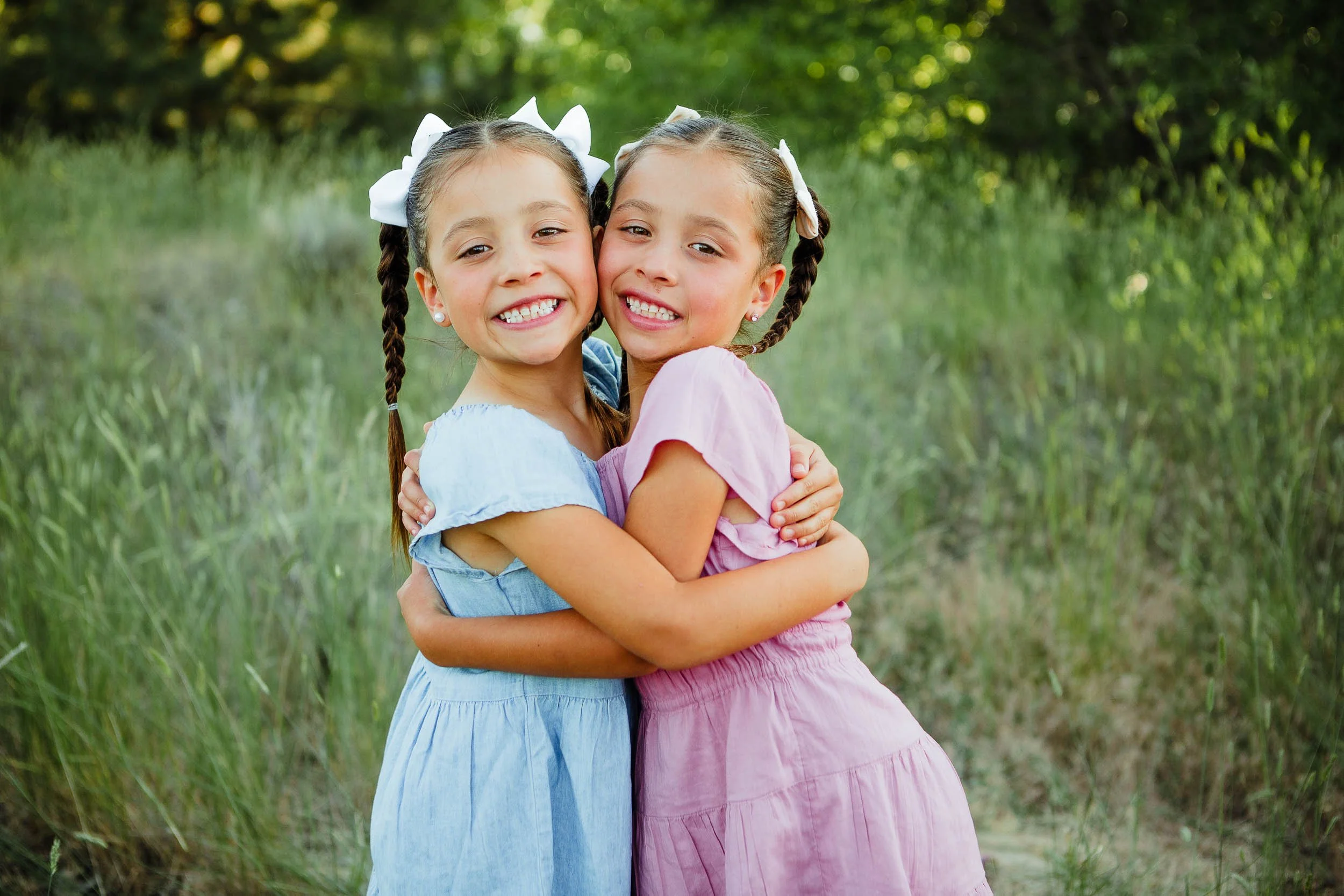 Twin girls hugging with faces close together
