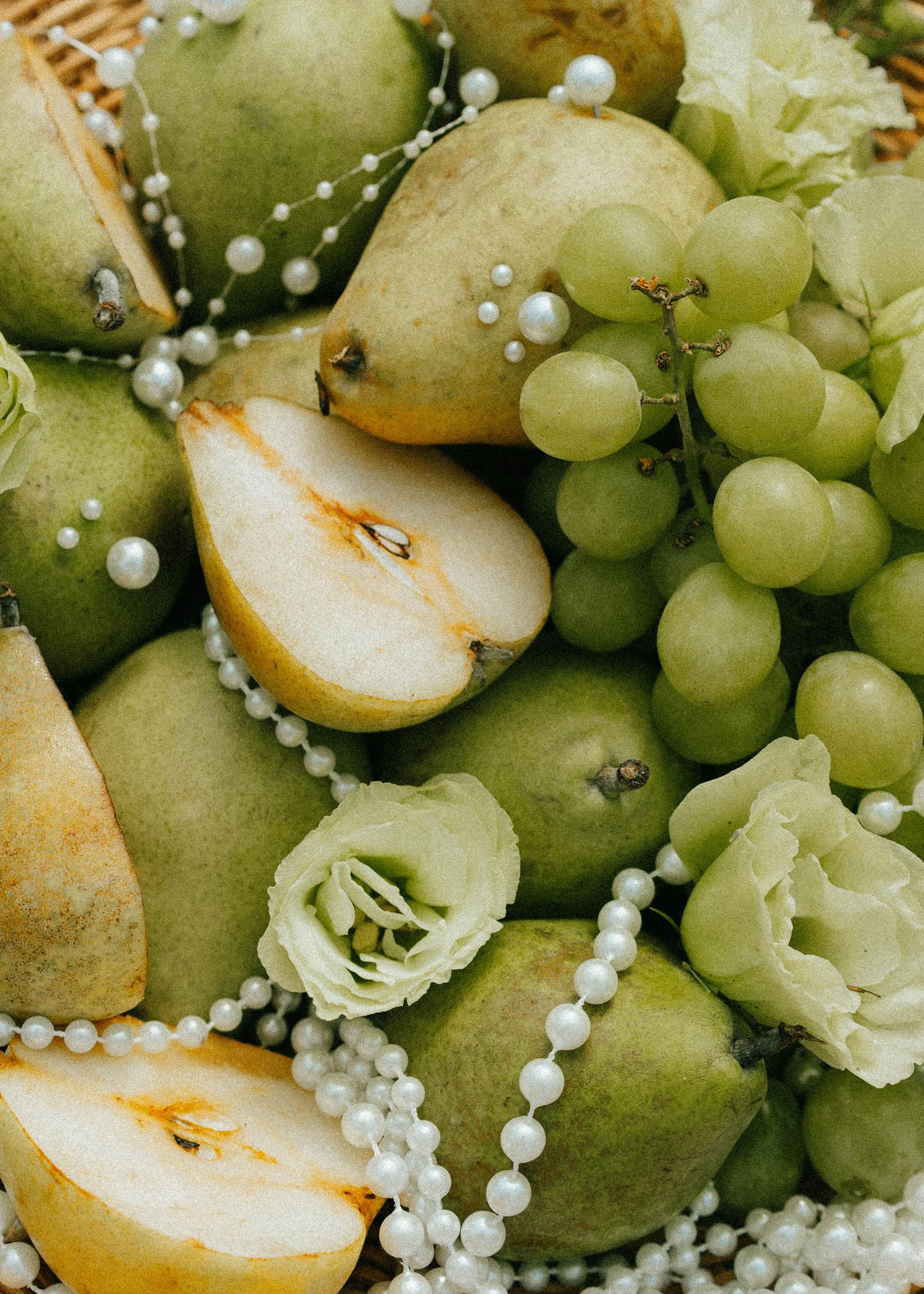 Green apples, green grapes, and white flowers with pearl necklaces.