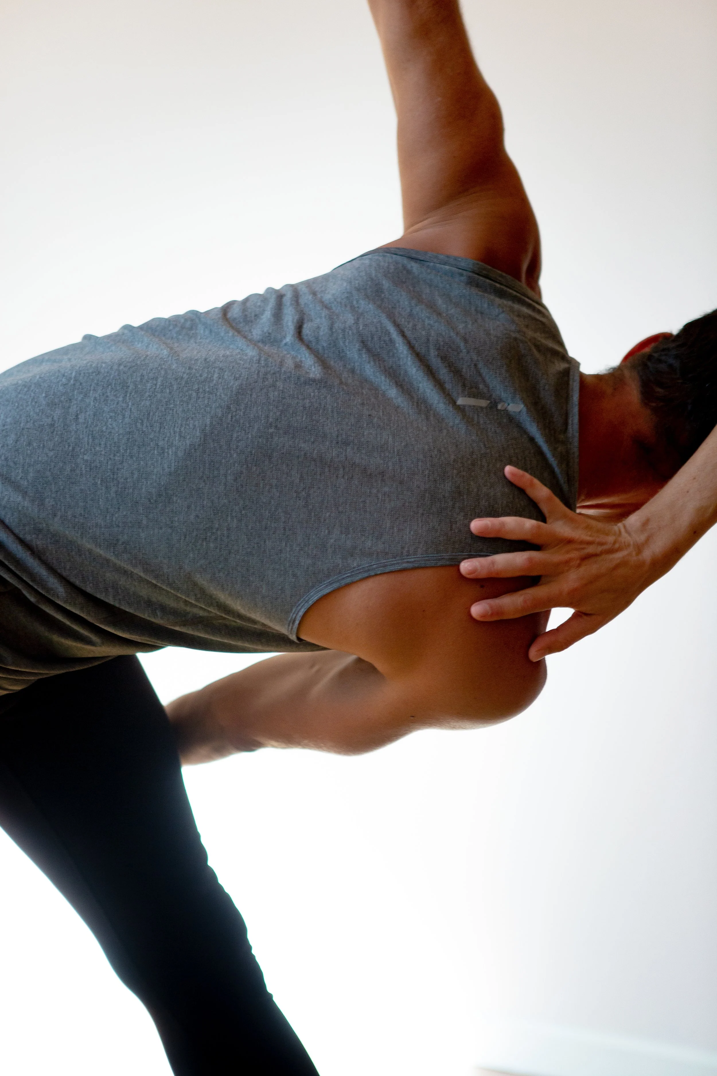 Yoga student doing a twist with teacher assisting