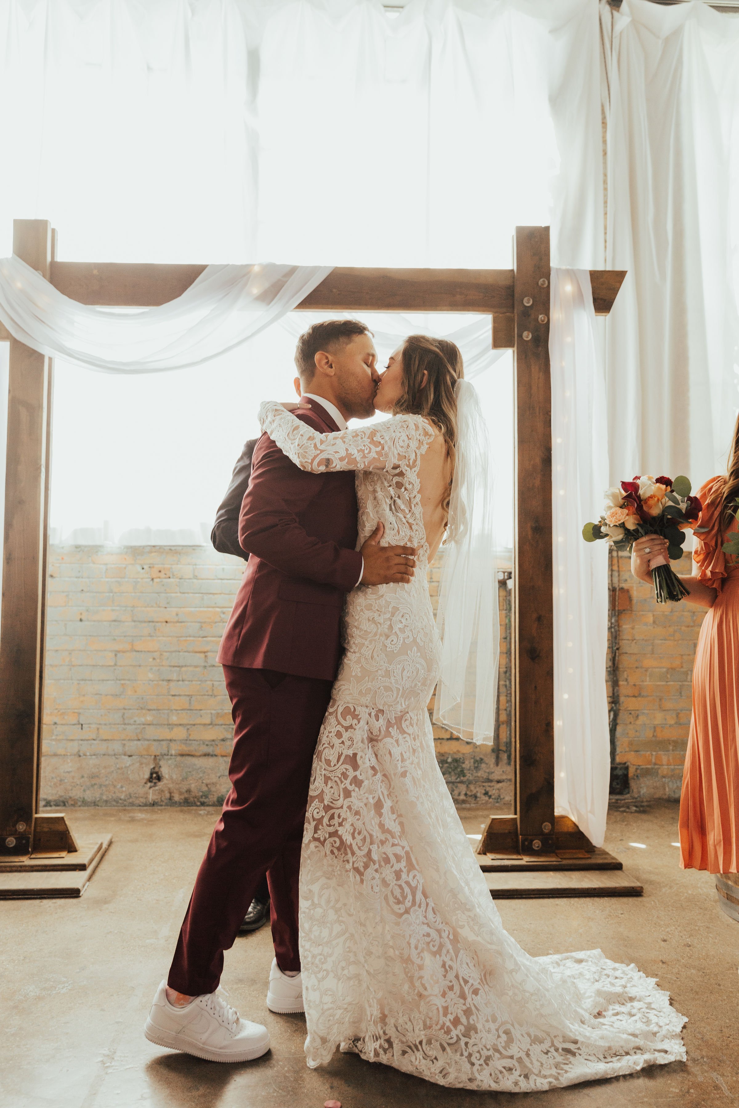Bride and Groom kiss in front of the event space arch