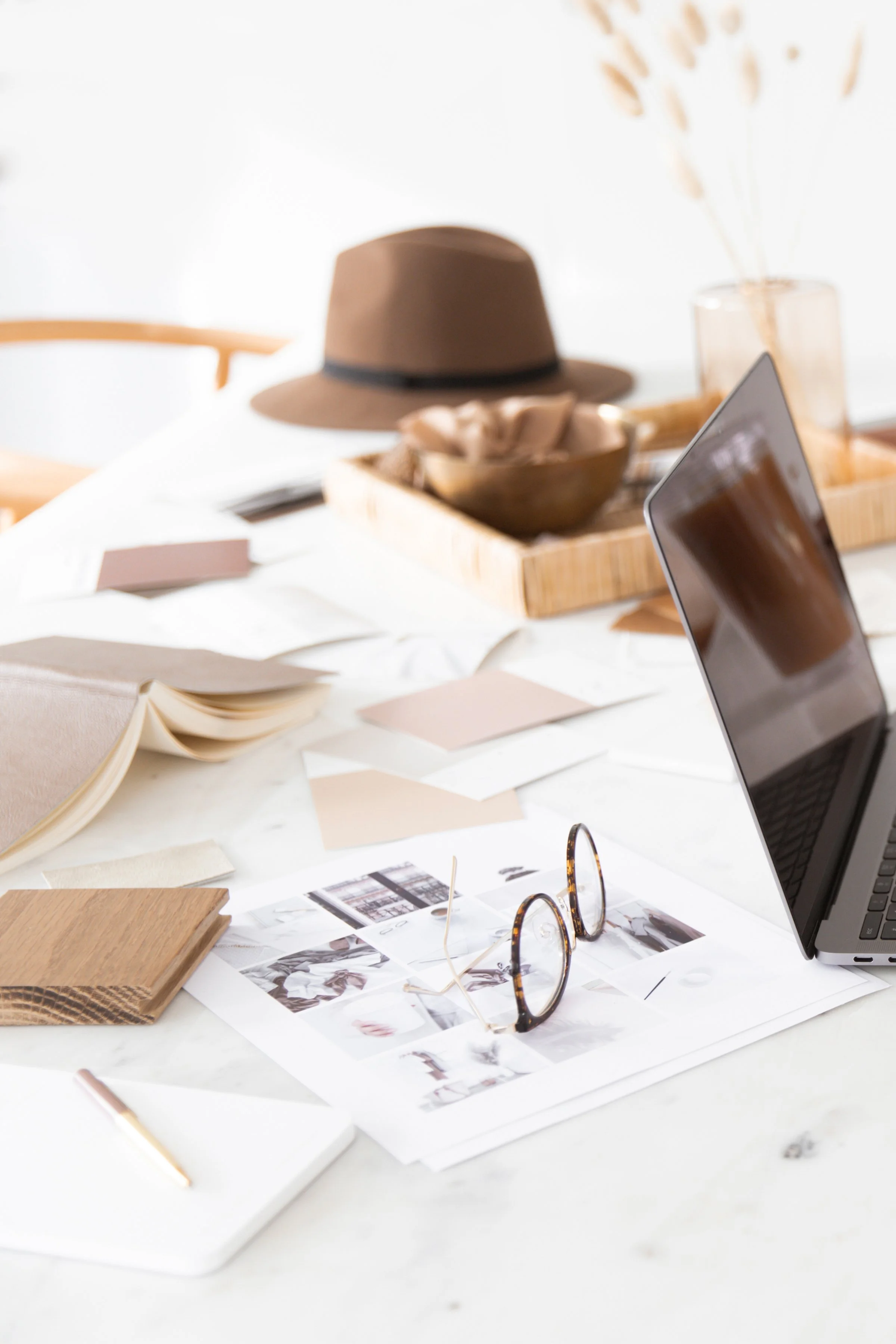 Creative workspace with laptop, mood board, glasses, notebook, and design materials