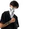 Young man with dark hair wearing a black shirt and a white face covering with bold black text, holding a black bag, against a plain white background.