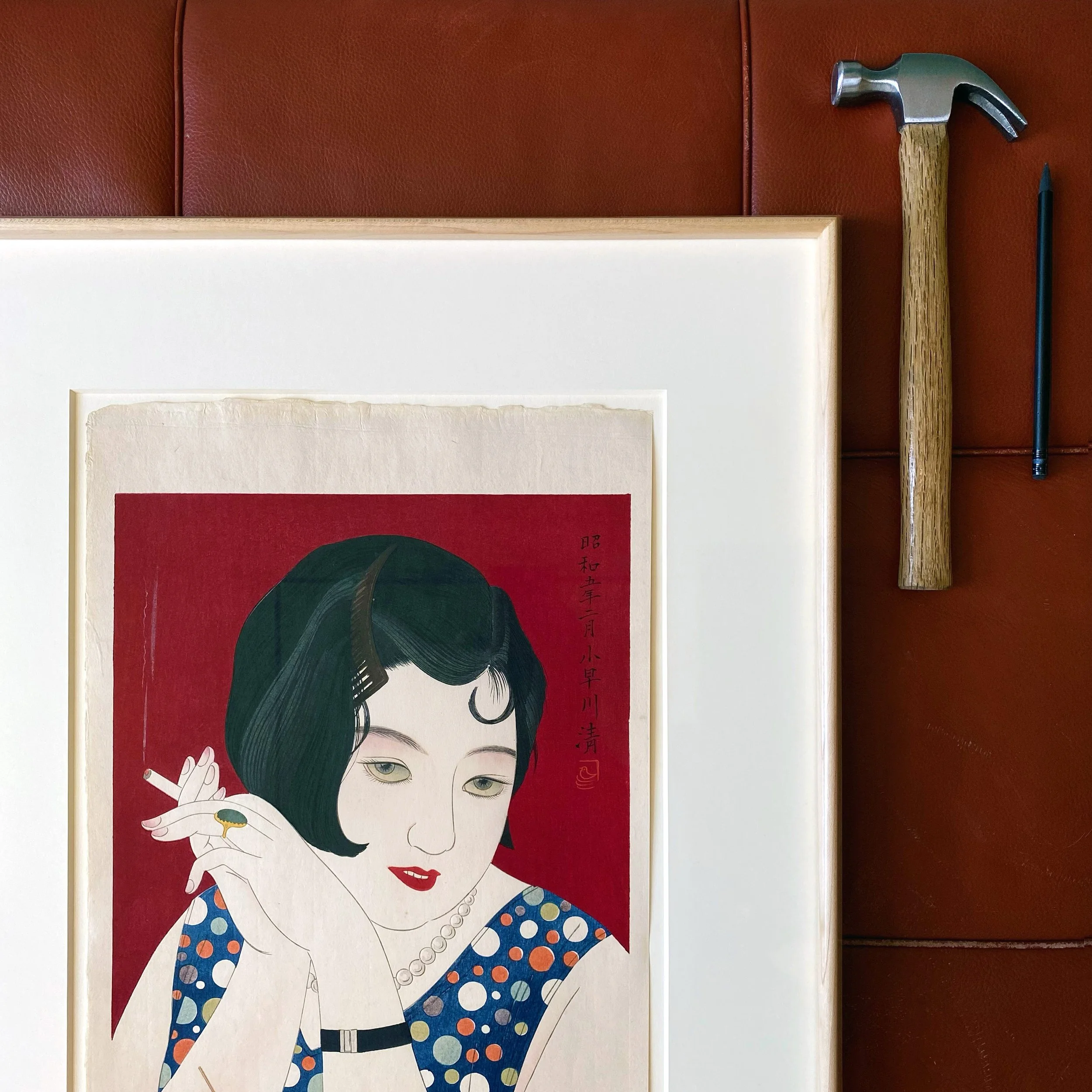 Colorful poster of a woman with short black hair, red lipstick, and pearl necklace, wearing a polka-dot dress, holding a cigarette.