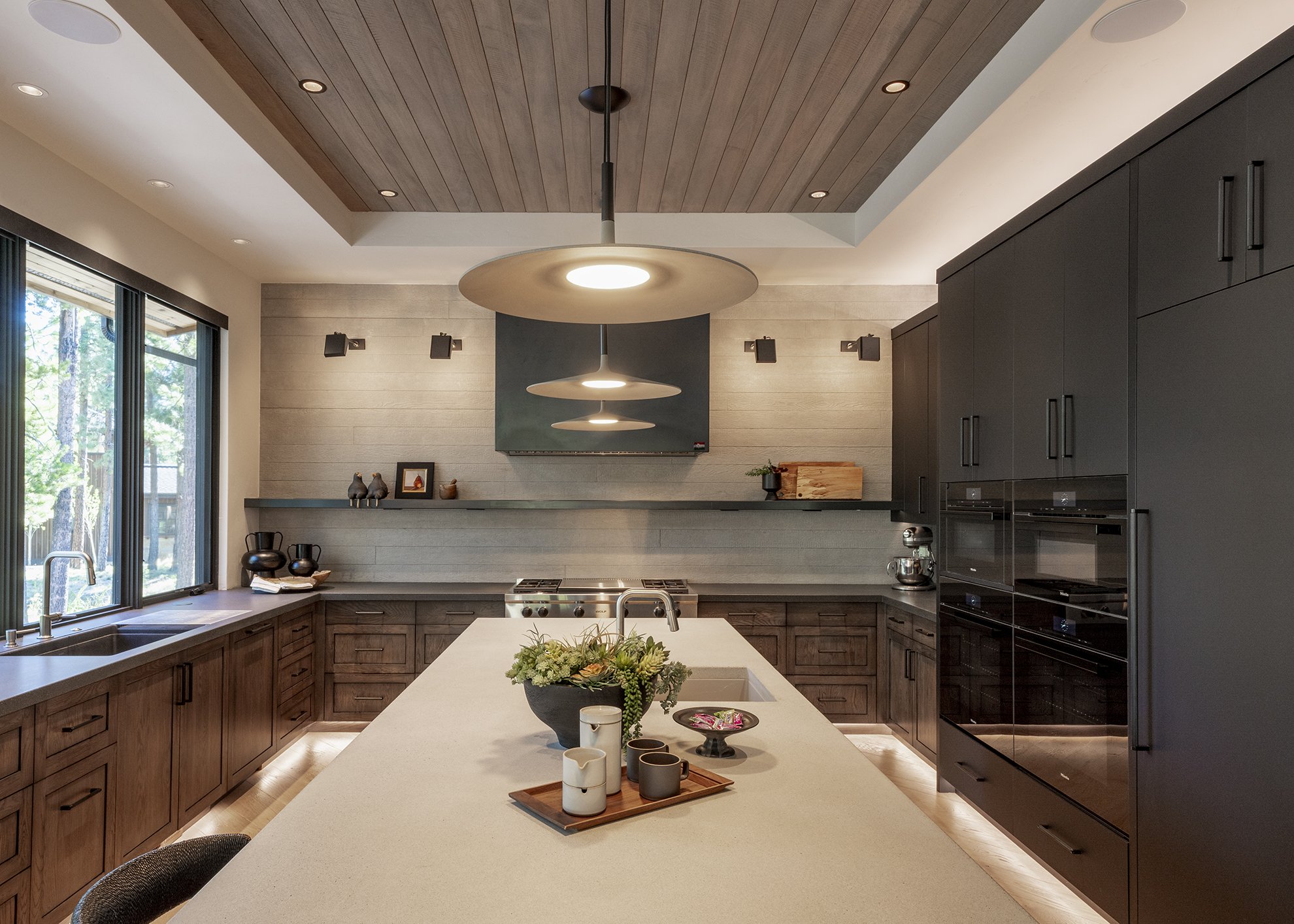 View of contemporary kitchen designed by Griffin Home Design. Features two countertops: a center island and wrap around at the sides with two colors of custom concrete. The Wrap around has solid wood cabinetry and the island and end wall have a custo
