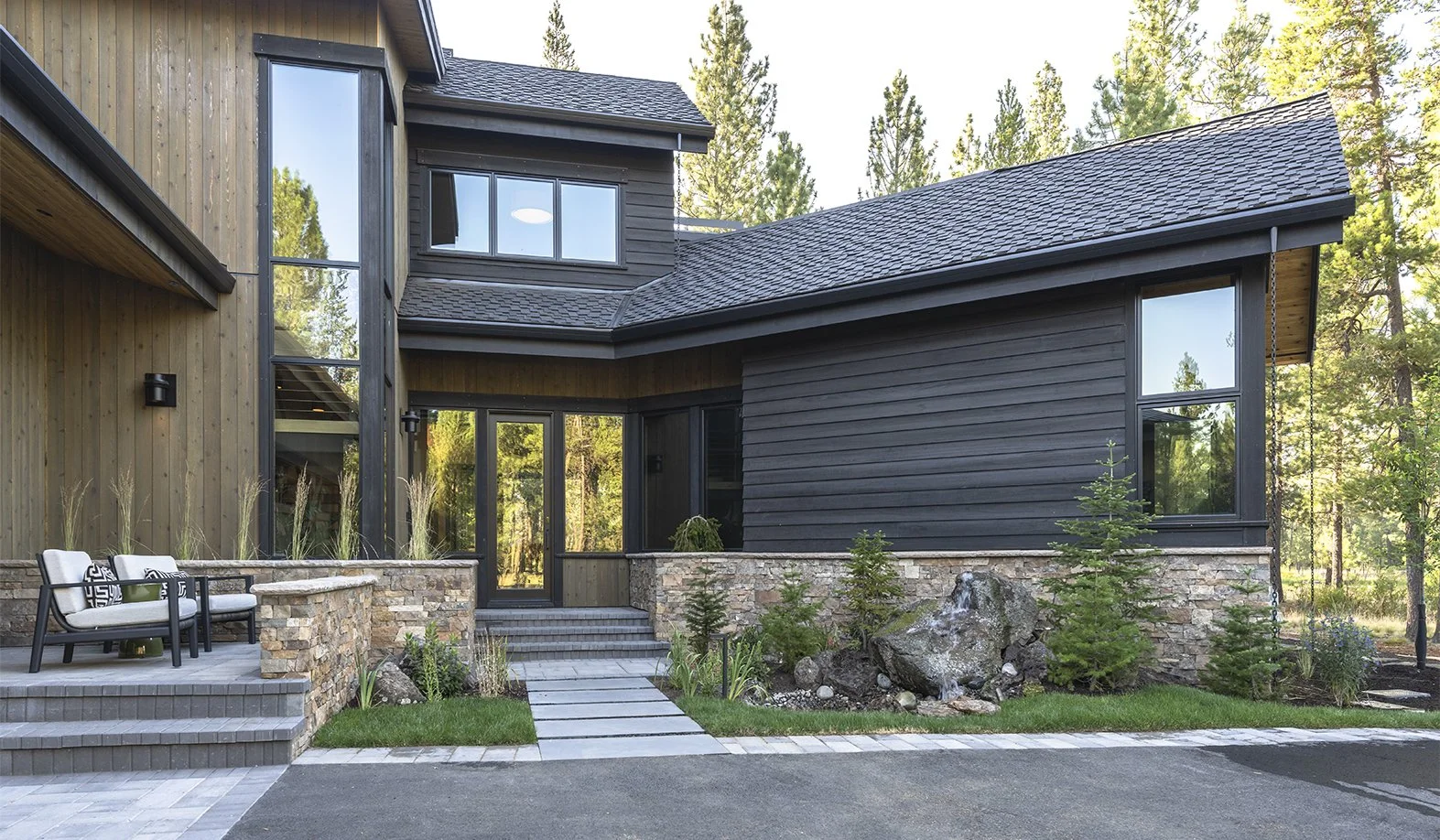 Modern Entry with vertical channel siding and horizontal Shou Sugi Ban siding. Two chairs are on a side entry porch.