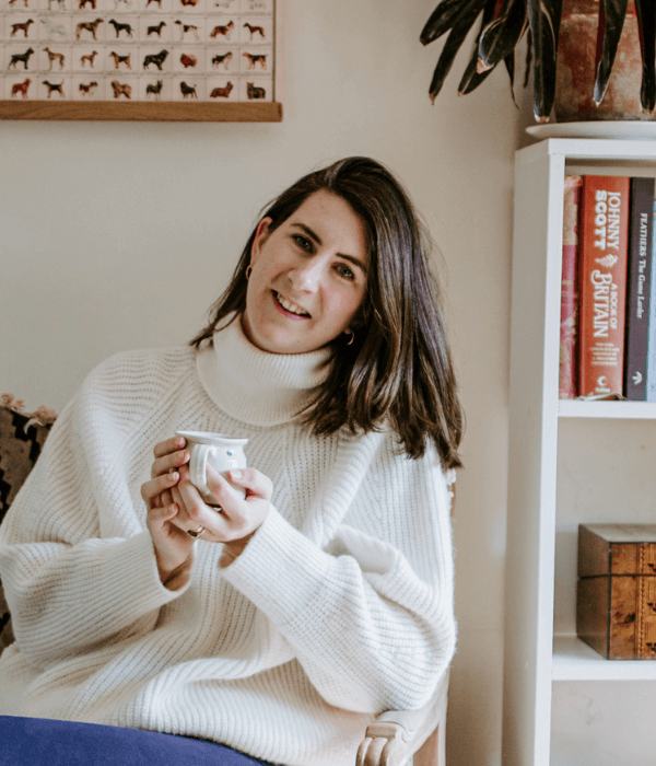 Josephine Brooks wearing a white jumper drinking tea.png