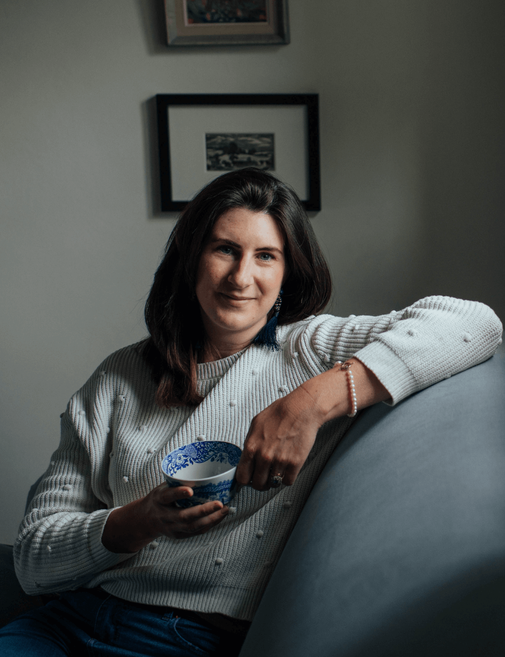 Josephine Brooks sat on a sofa drinking tea.png