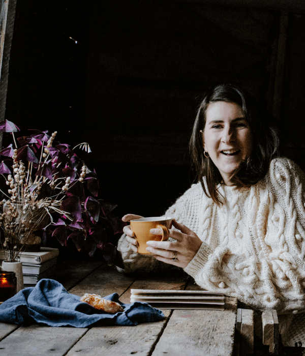 Josephine wearing a cosy jumper holding a cup of tea