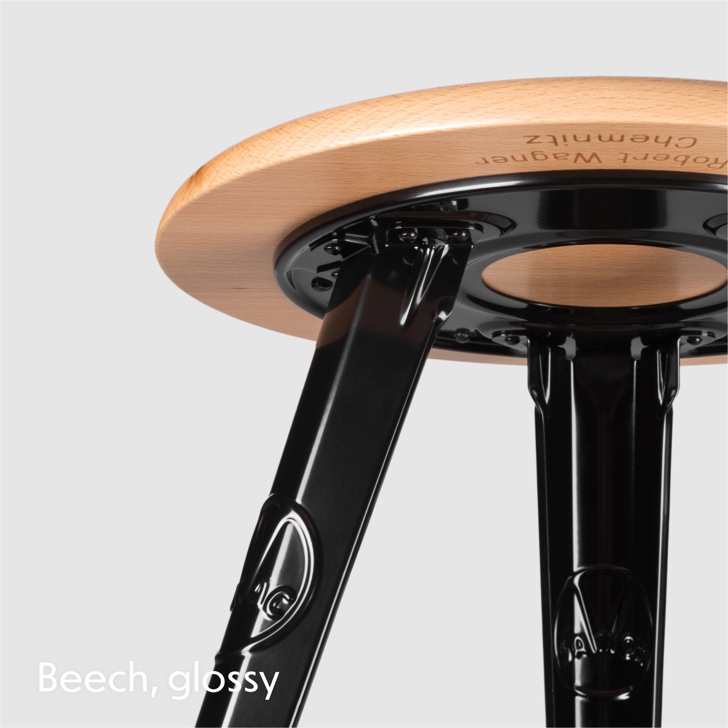 Rowac Model 1 industrial Schemel or workshop stool – detail view of riveted metal or steel leg and seat base. Beech seat top and frame in glossy black.