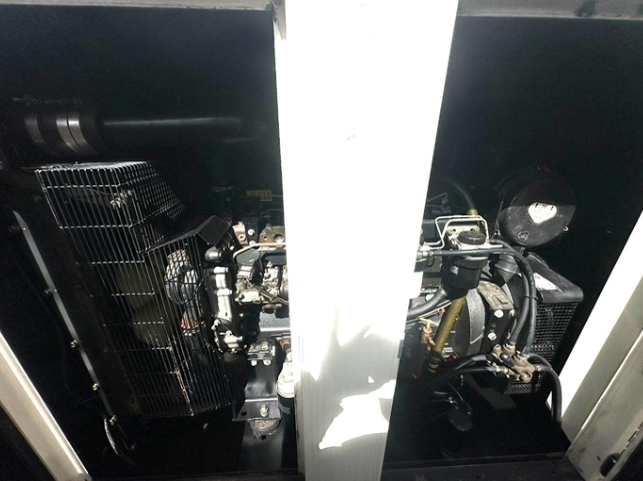 View of two industrial generators or machinery housed within a compartment, separated by a white partition, with various pipes and components visible.