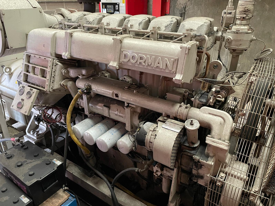 A large industrial Dorman engine with various pipes and components, situated in a factory or workshop setting.