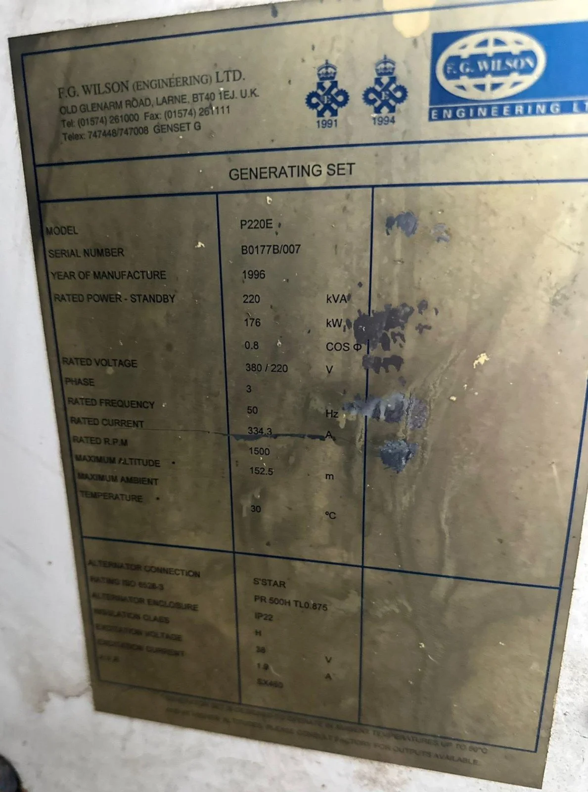 Metal nameplate for a generator set by F.G. Wilson Engineering Ltd., showing specifications such as model P220E, serial number B0177B/007, manufactured in 1996, rated power 220 kVA, 176 kW, voltage 380/220V, phase 3, frequency 50Hz, current 334.3A, m