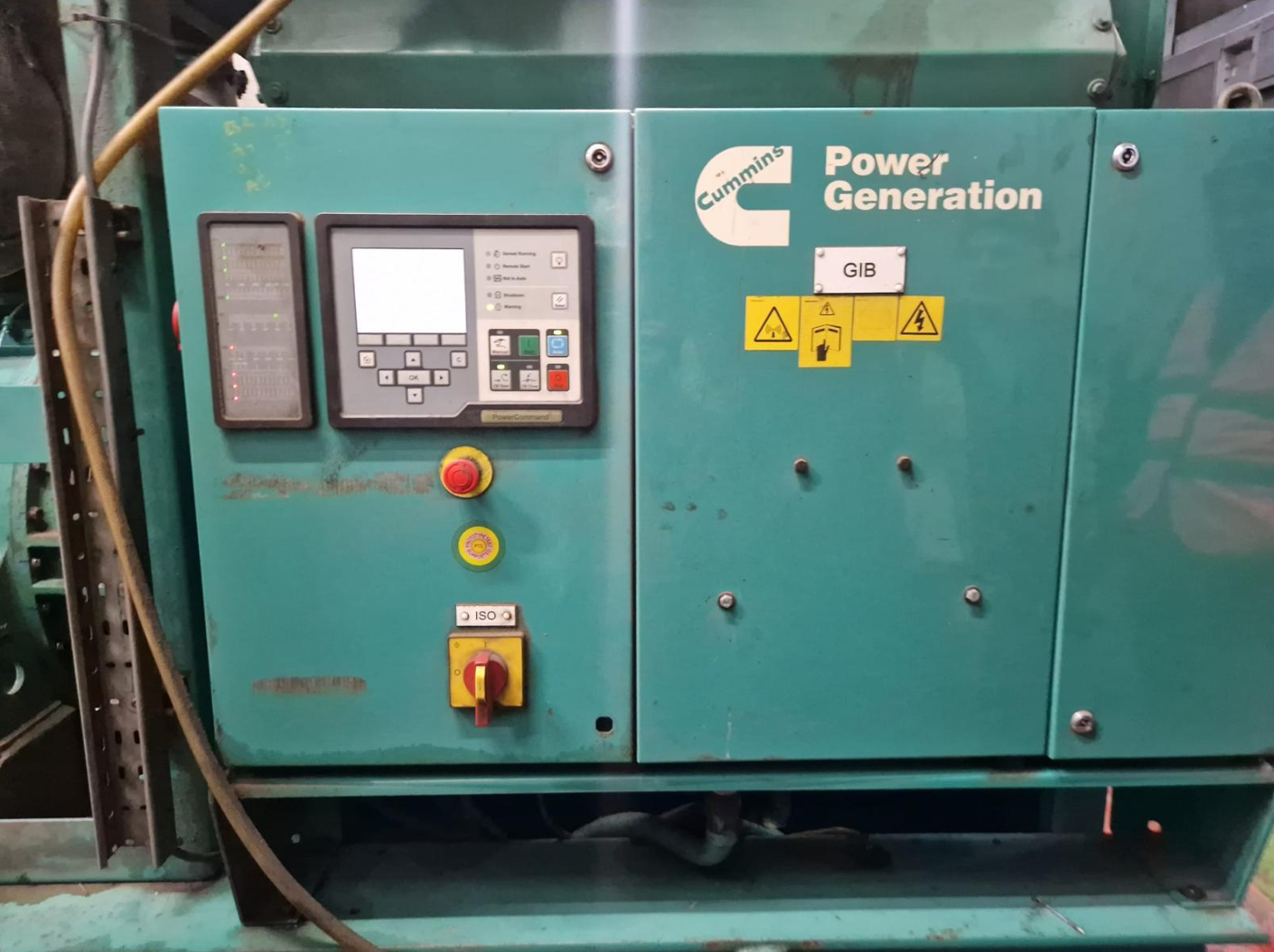 Industrial power generator with control panel, labels, and warning symbols.