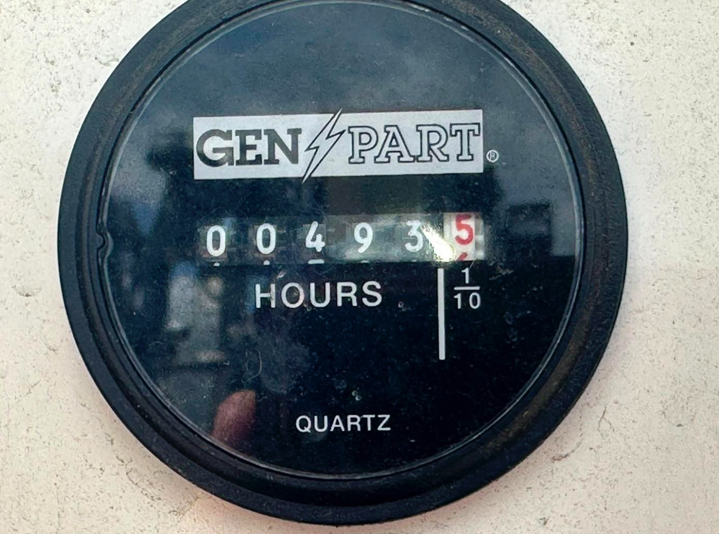 Black analog hour meter with the label 'GEN PART' and a logo with a lightning bolt, displaying 0493.5 hours. The background is a light-colored surface.