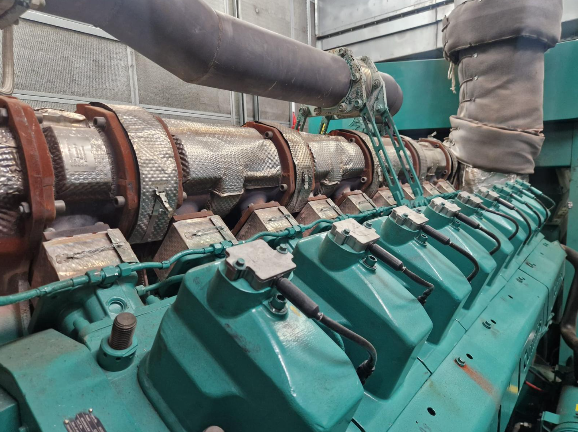 Industrial machinery with teal components and large pipes.