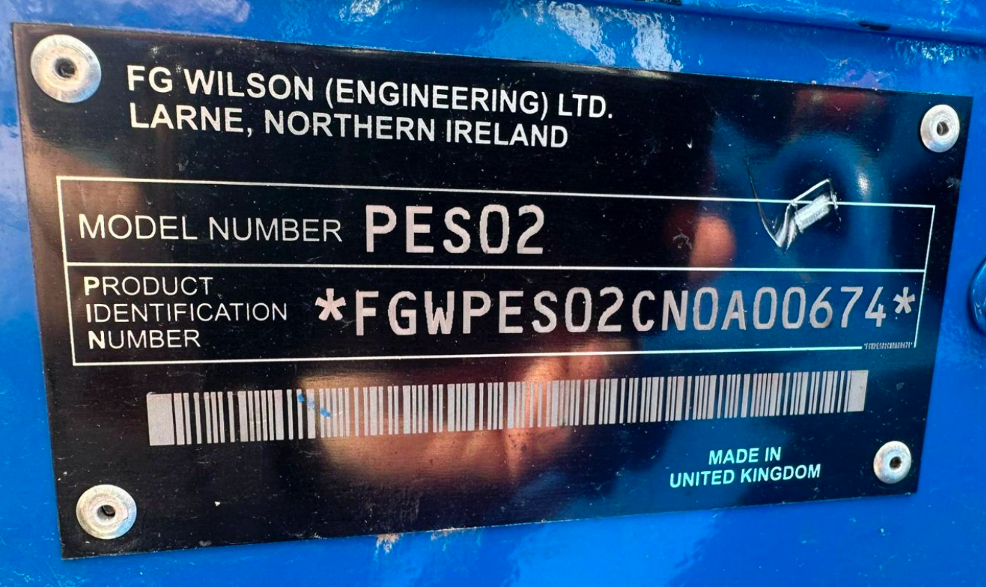 Close-up of a black metal identification plate on a blue machine, showing manufacturer FG Wilson Engineering Ltd, located in Larne, Northern Ireland. The plate includes model number PES02, product identification number FGW P E S 02 C N A 0 0 6 7 4, a