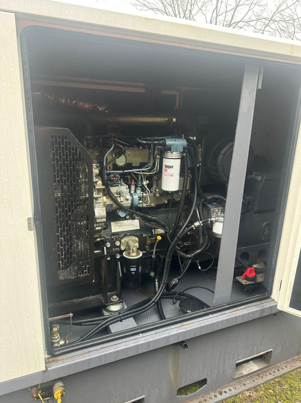 Open panel revealing industrial generator with engine, filters, and electrical components inside a metal enclosure.