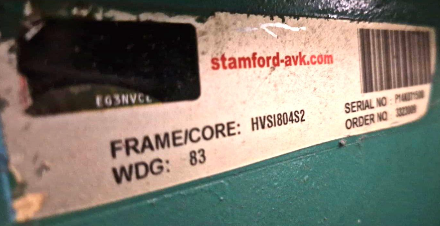 A partial view of a product label with the website 'stamford-avk.com' in red text, a barcode, and details including frame/core number, serial number, WDG, and order number on a green surface.