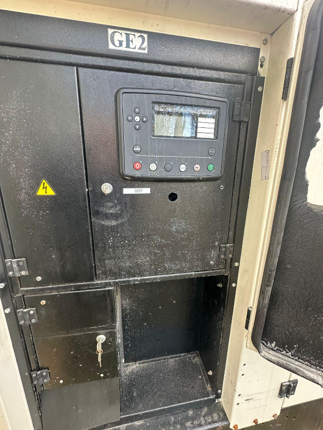 Close-up of a black industrial control panel with buttons, a display screen, and a key lock, labeled GE2.