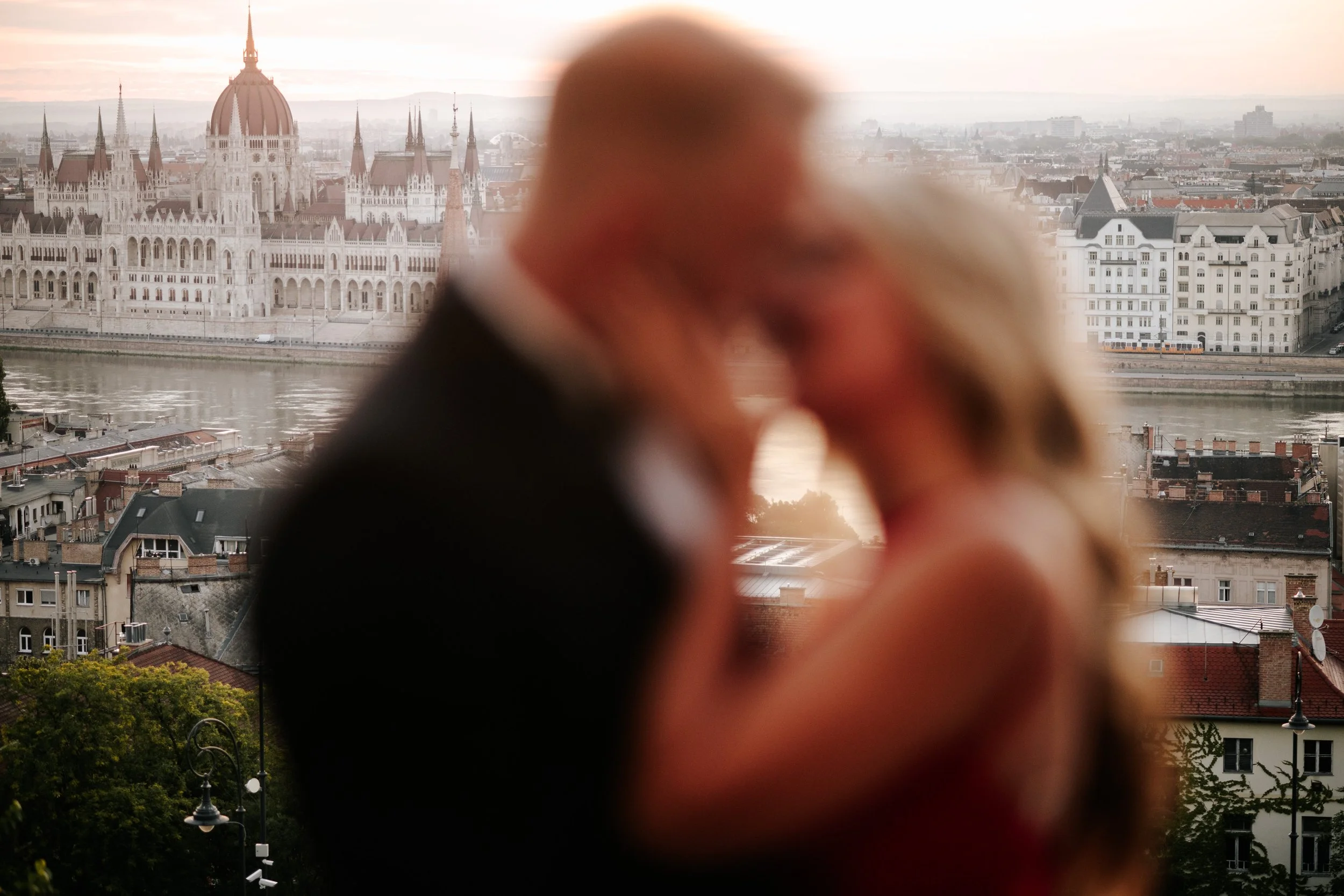 The Hungarian Parliament in focus behind the couple’s softly blurred embrace