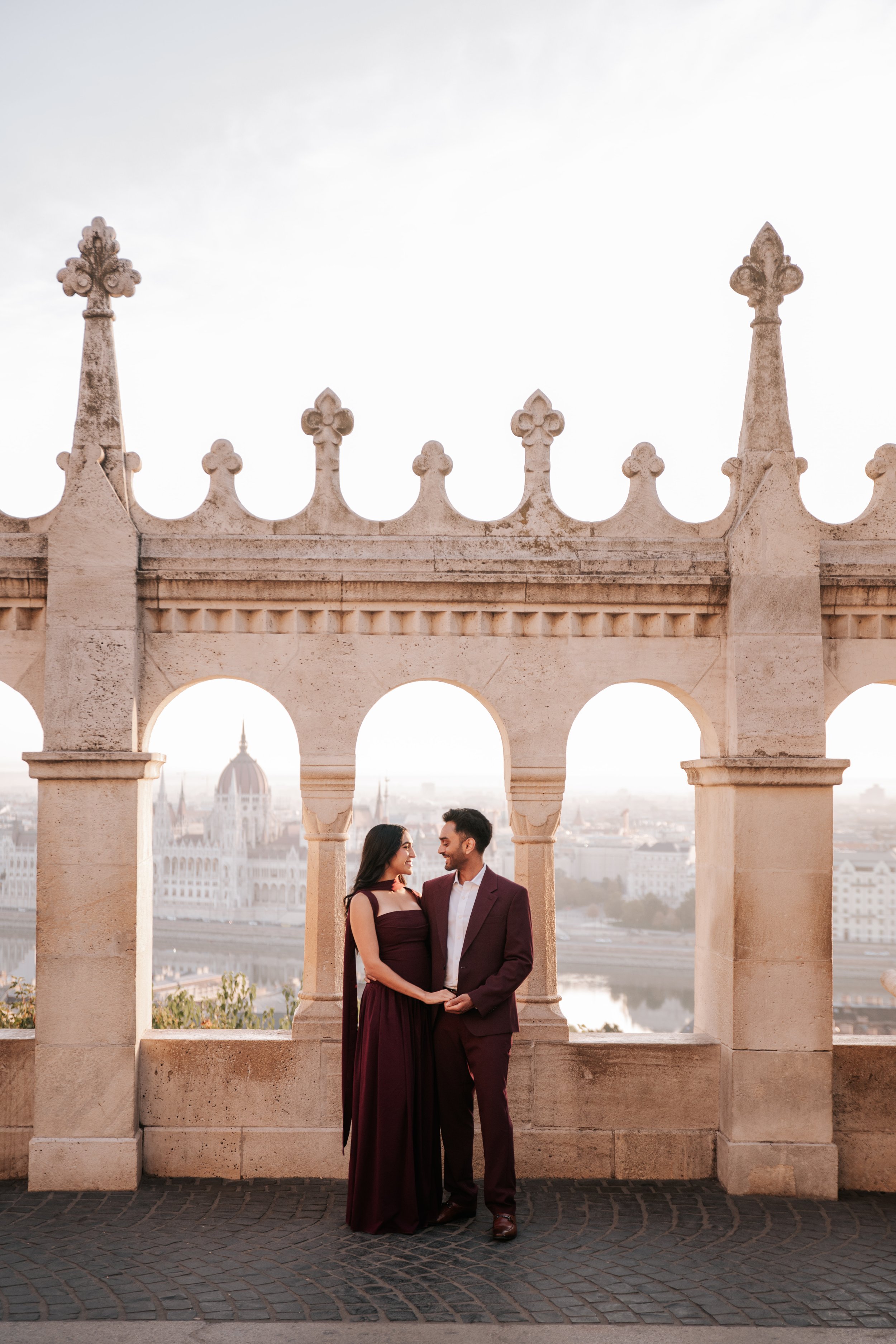 Couple in matching burgundy outfits beneath the arches of Fisherman’s Bastion