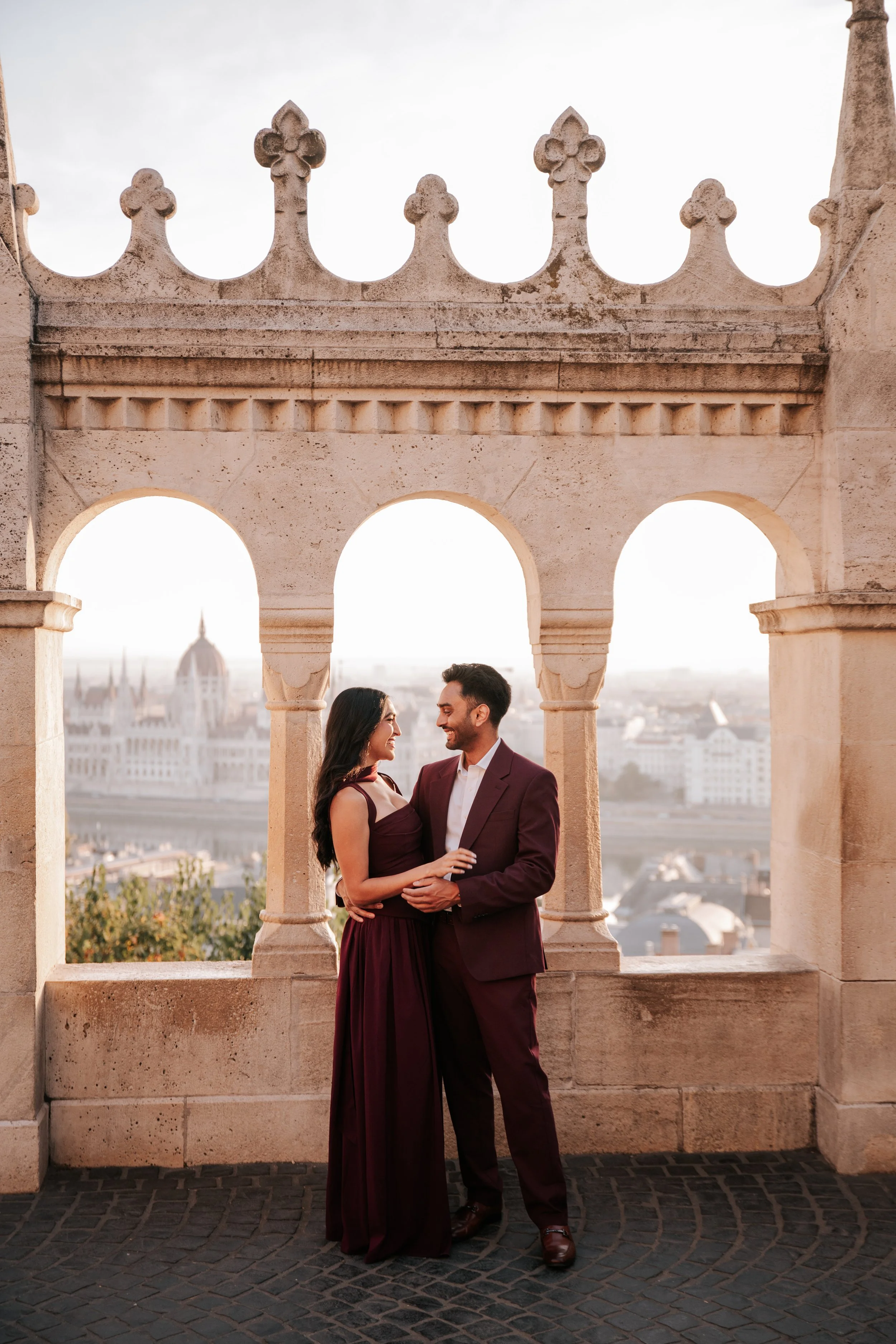 Facing each other beneath the stone arches, with Parliament across the Danube⁠