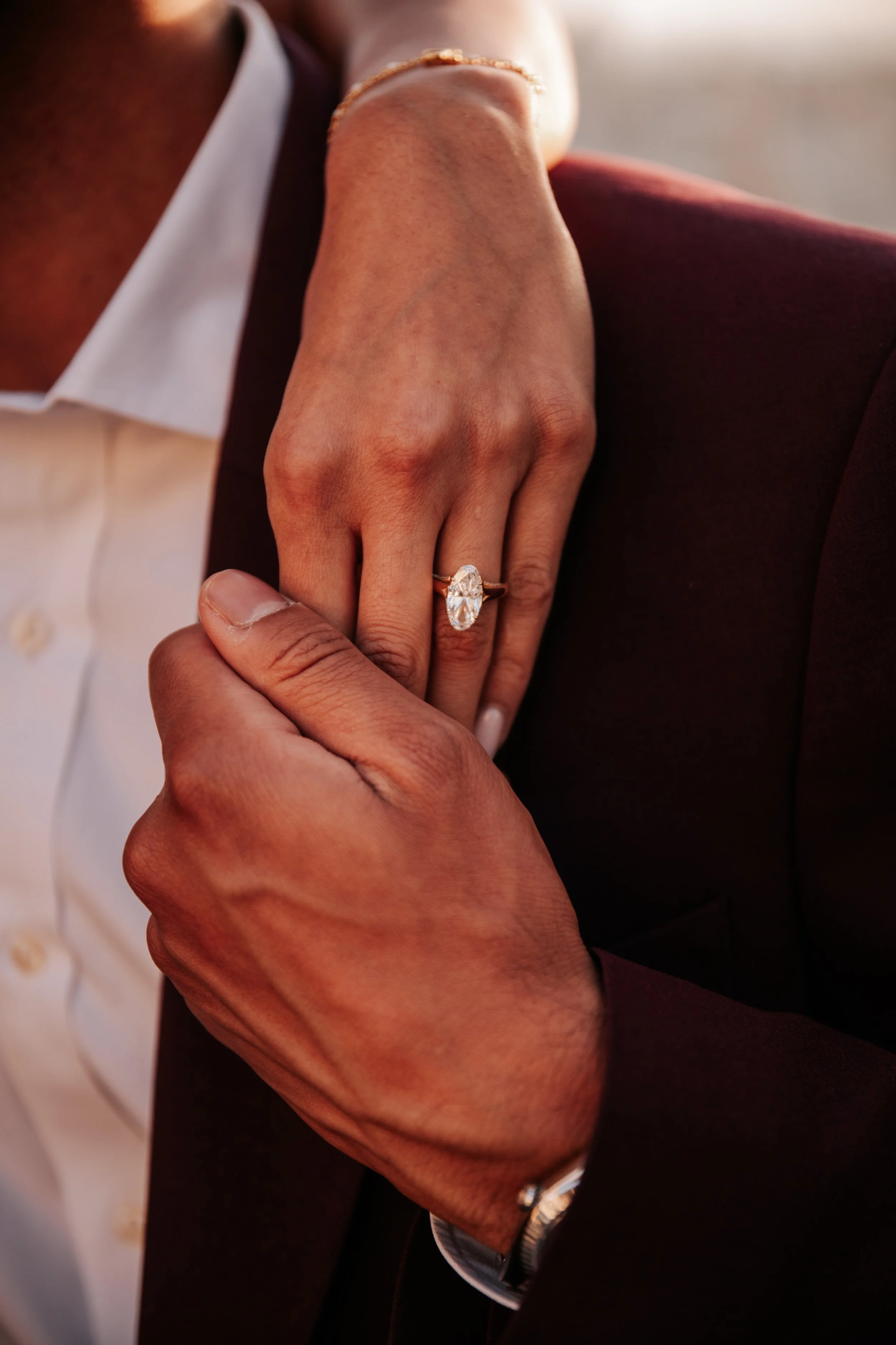 Detail of her engagement ring against his burgundy suit
