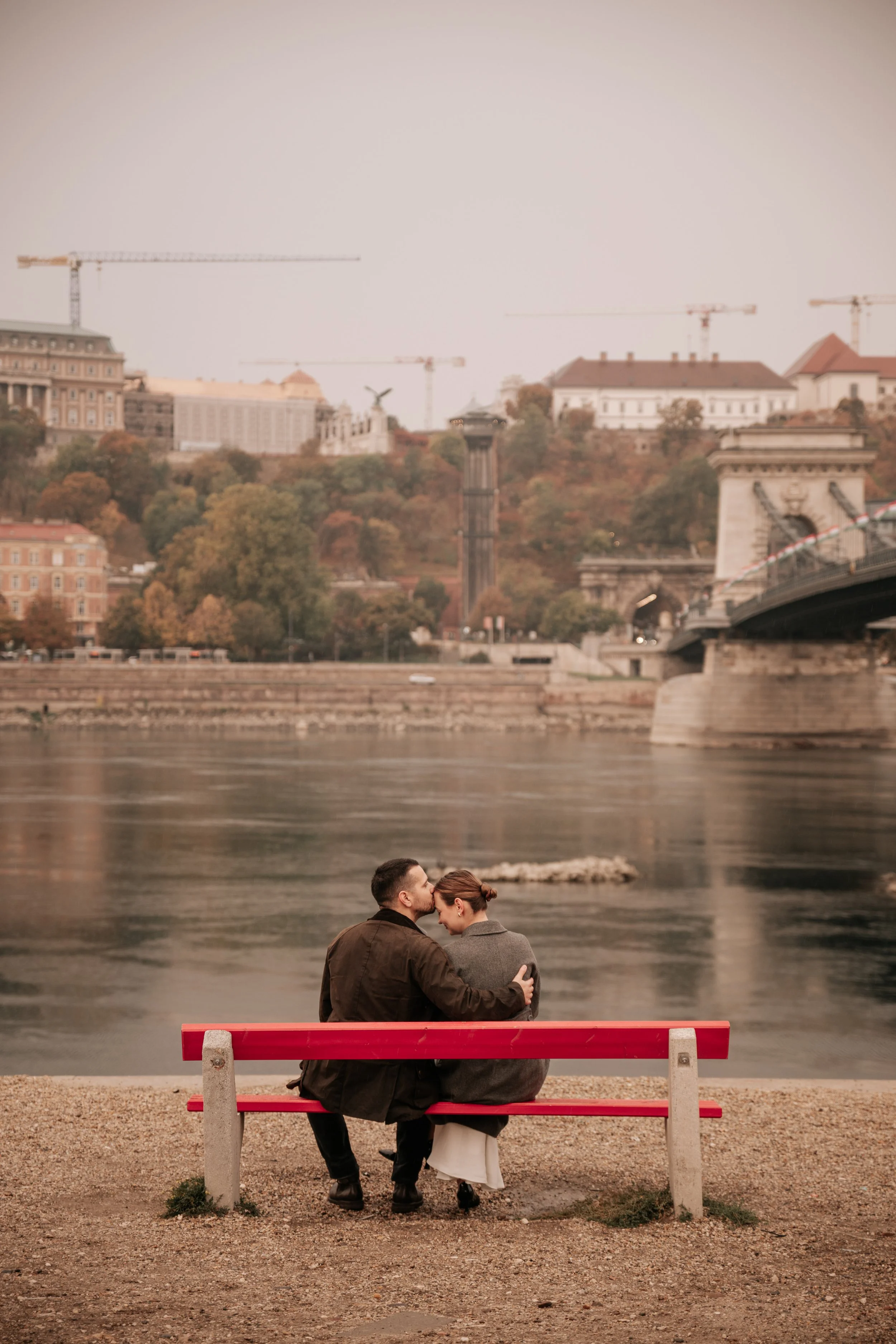 Post-proposal couples photography on a red bench beside the Danube