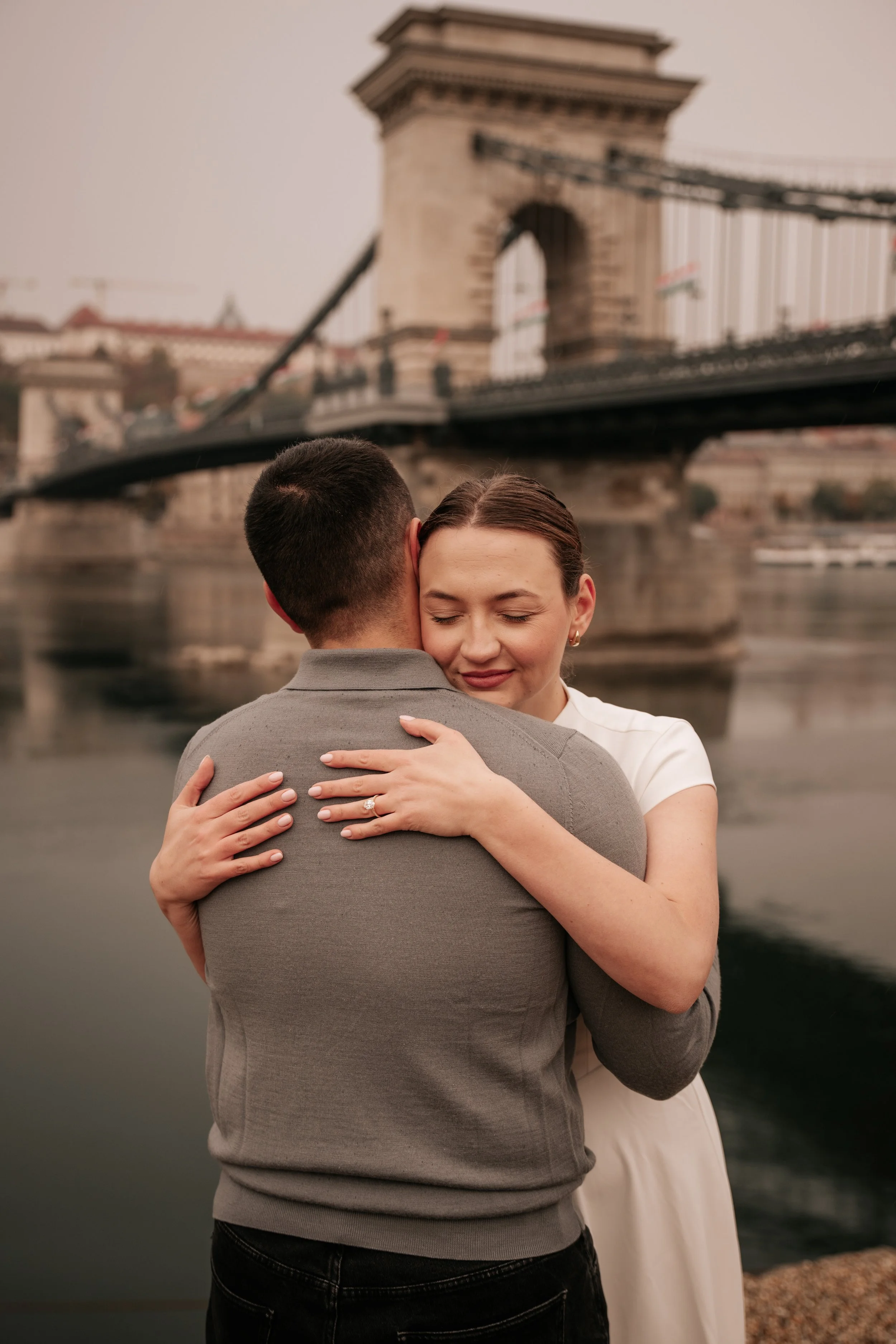 An embrace after the proposal, photographed with the Chain Bridge behind them