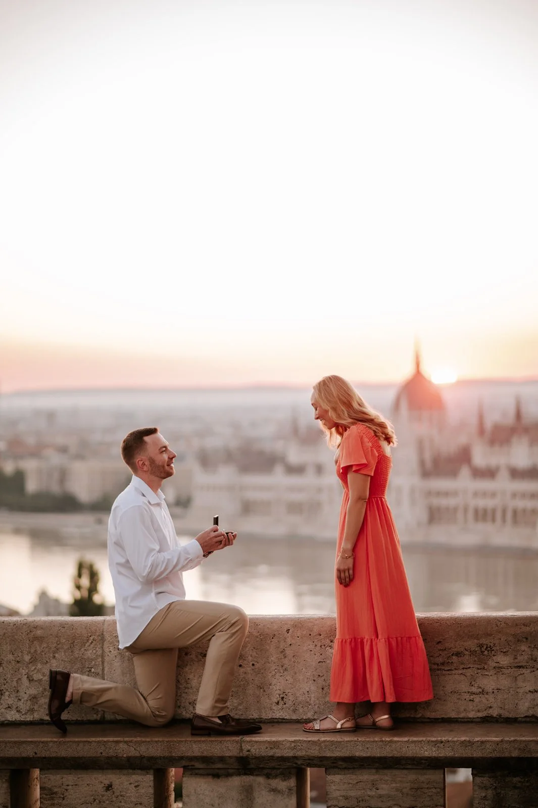 Man proposing at sunrise with the Budapest Parliament glowing in the background.