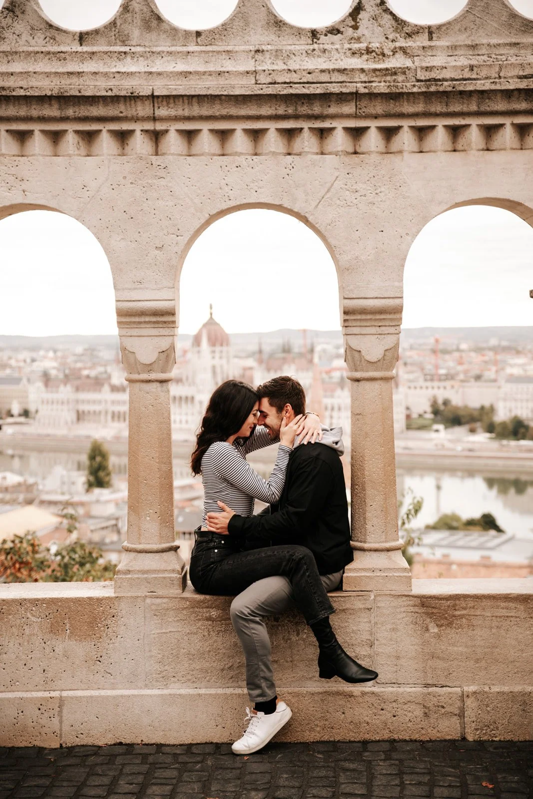 A couple sharing a quiet moment between the arches of Fisherman’s Bastion overlooking Budapest.