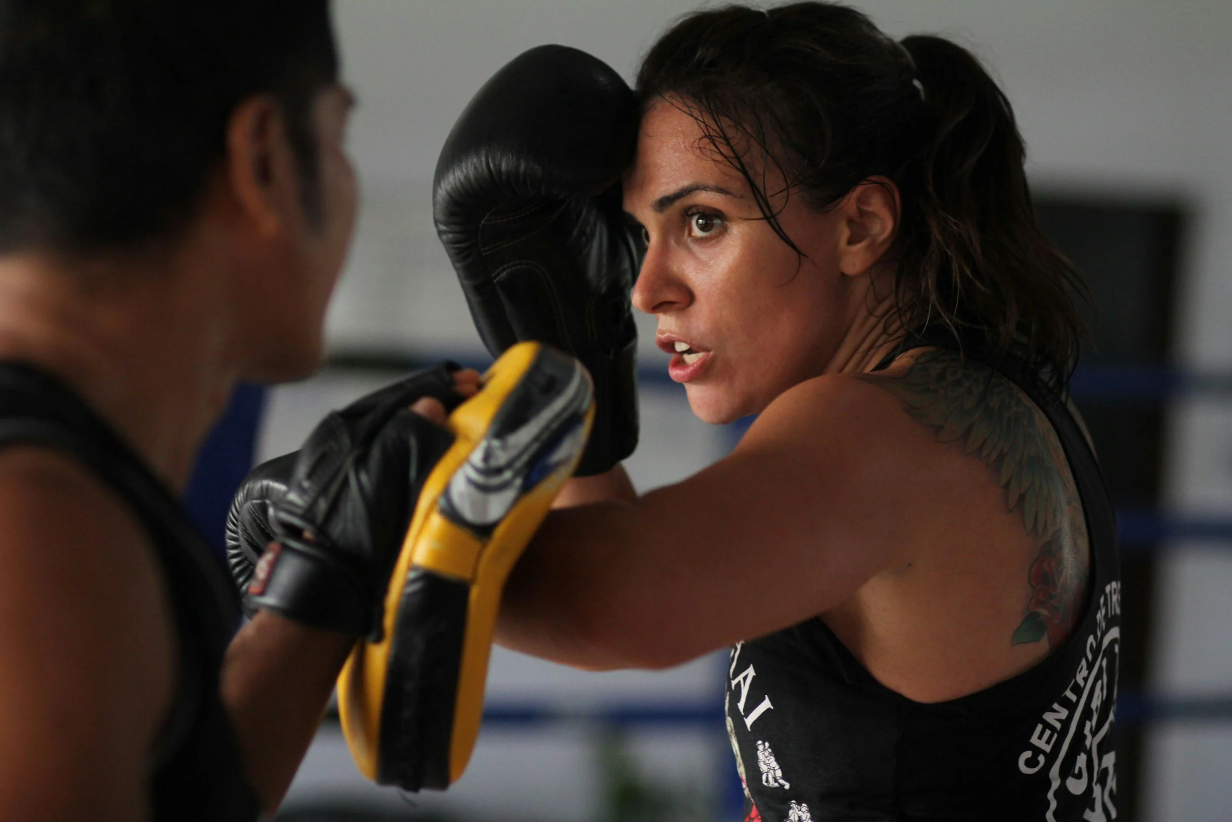 Woman training Muay Thai striking techniques with focus mitts during class at Elements MMA in Keene, NH