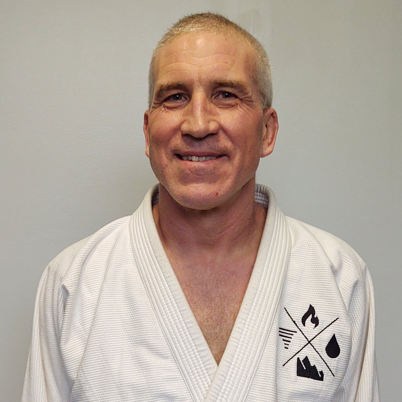 Kevin Warzecha, Judo instructor at Elements MMA in Keene, New Hampshire, wearing a white gi and smiling