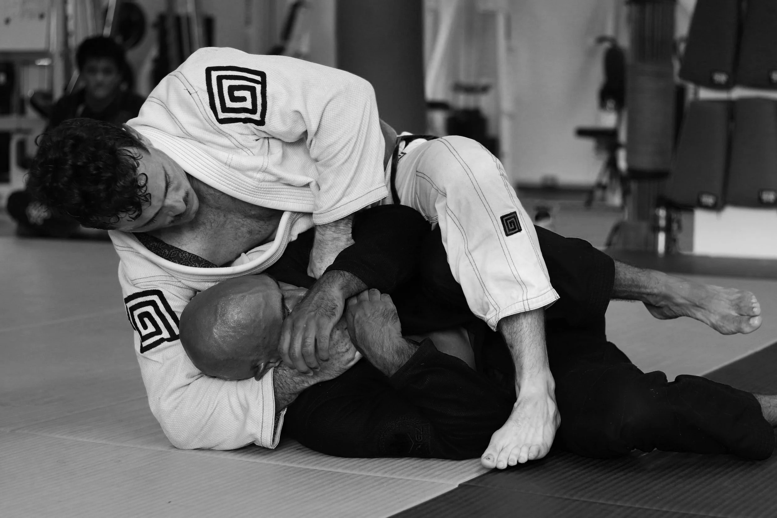 Two adult students training submission techniques in Brazilian Jiu-Jitsu gi class at Elements MMA in Keene, New Hampshire