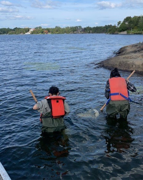 Cherokee (left) and Kessa (right) Chum kick-and-sweep to find aquatic insects as part of science learning activities with Laurentian University researchers and students.