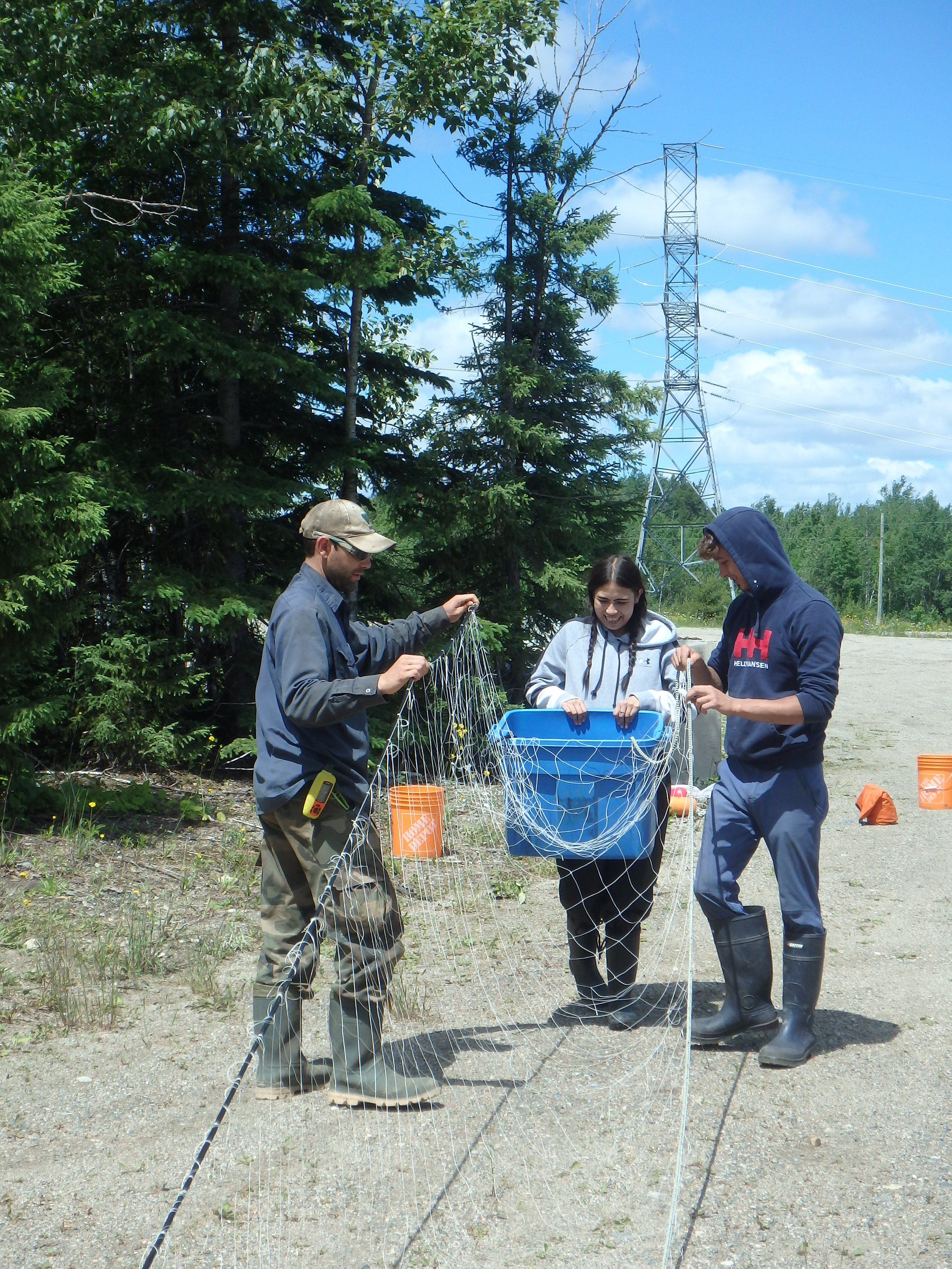 Jacob Seguin (WCS Canada, left), Ocean Skye Phillips (MCFN youth, center), and Justin Simard (MCFN youth, right) prepare a net together.