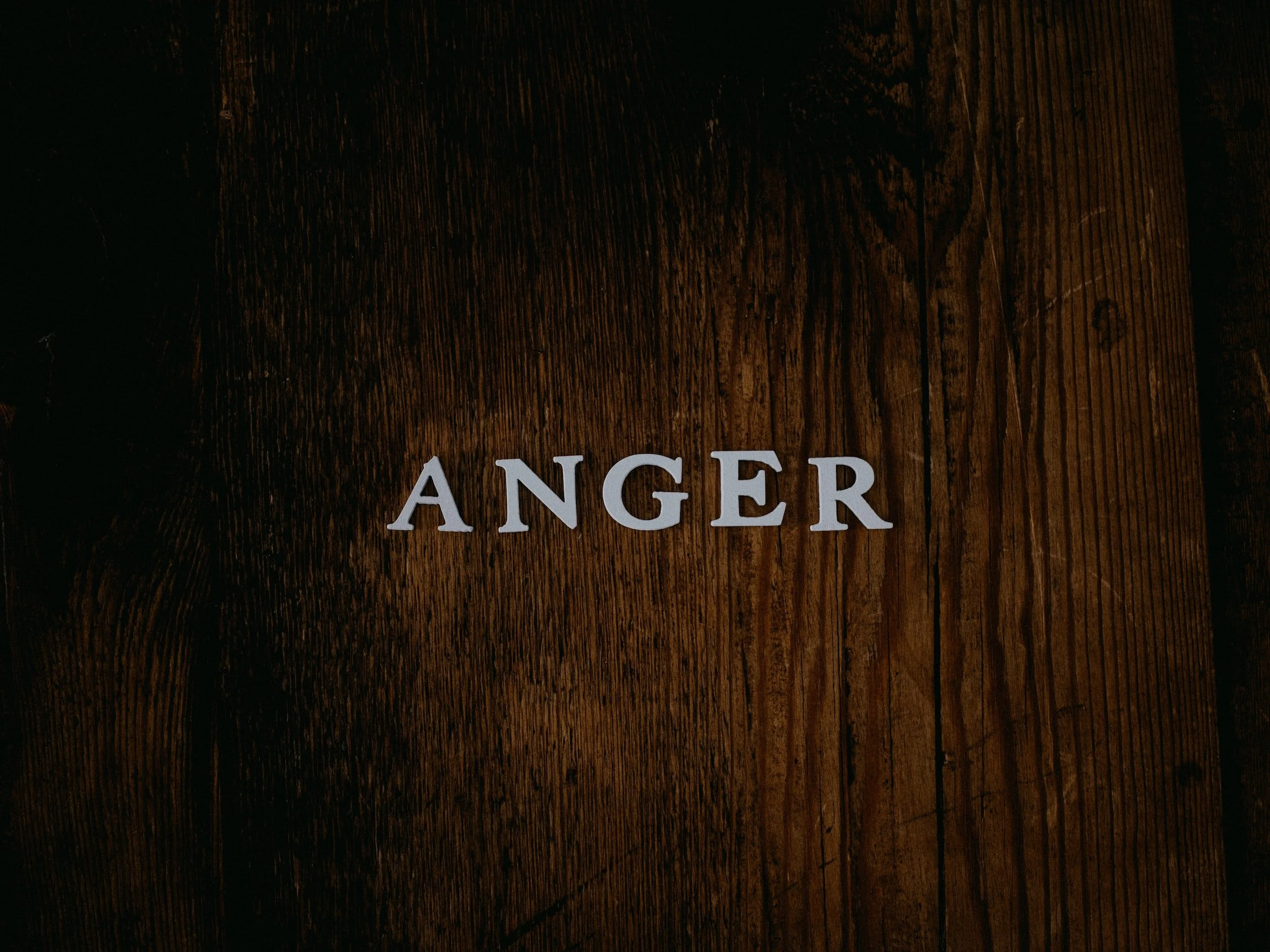 the word "anger" on the background of a woodgrain