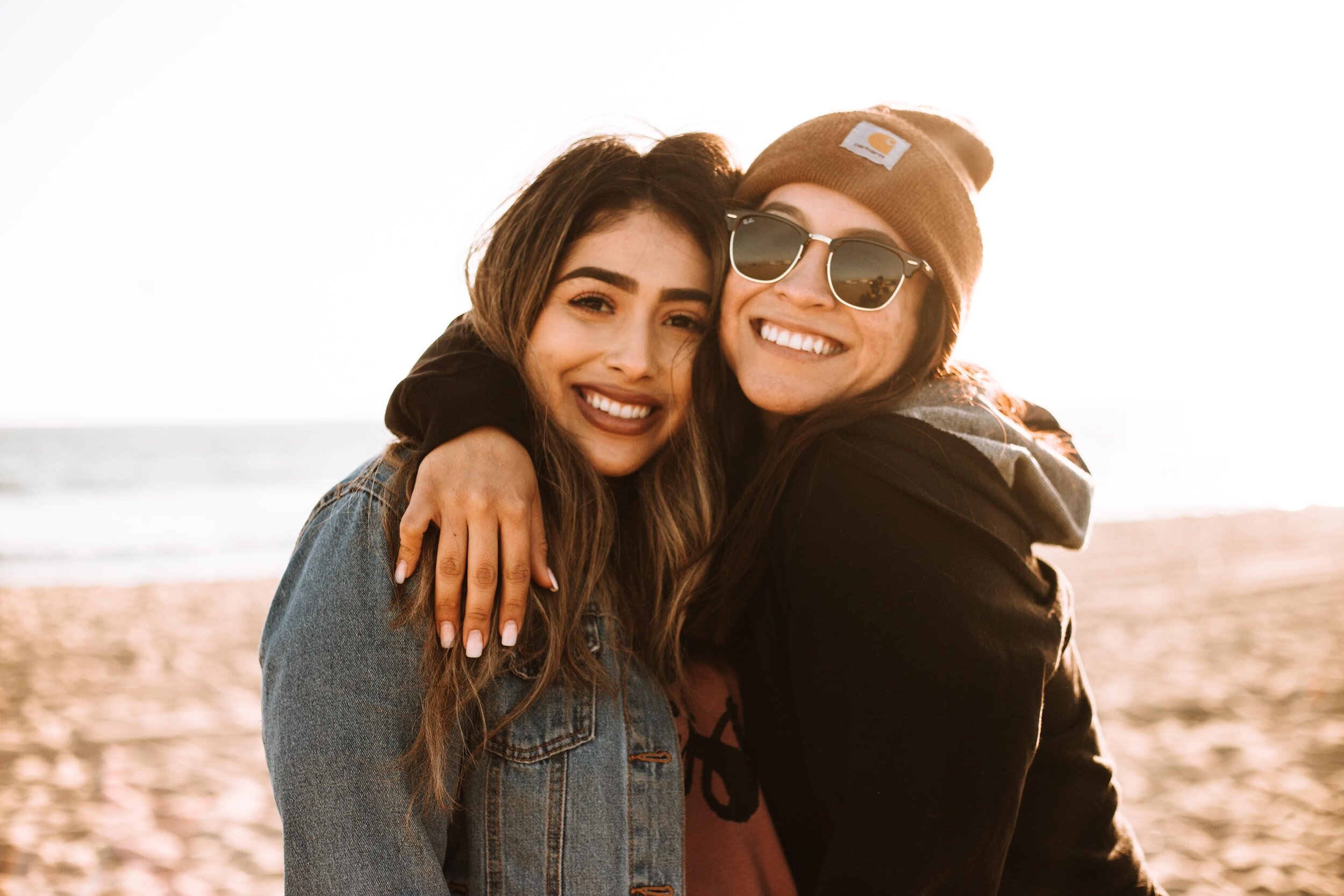 two women embracing on a beach showing their friendship