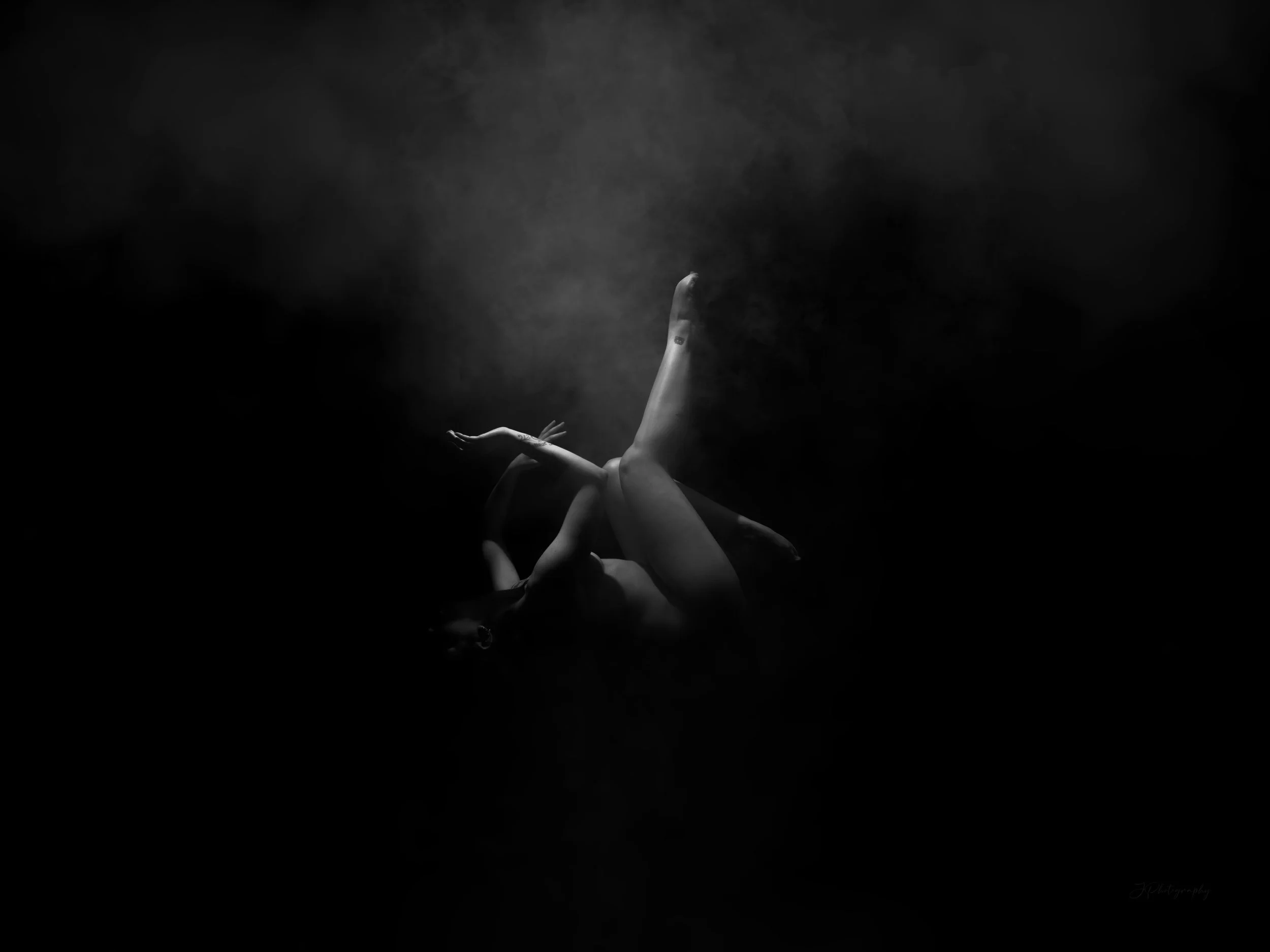 Une femme nue flottant dans l'eau dans une pose gracieuse, en noir et blanc, entourée d'une ambiance mystérieuse