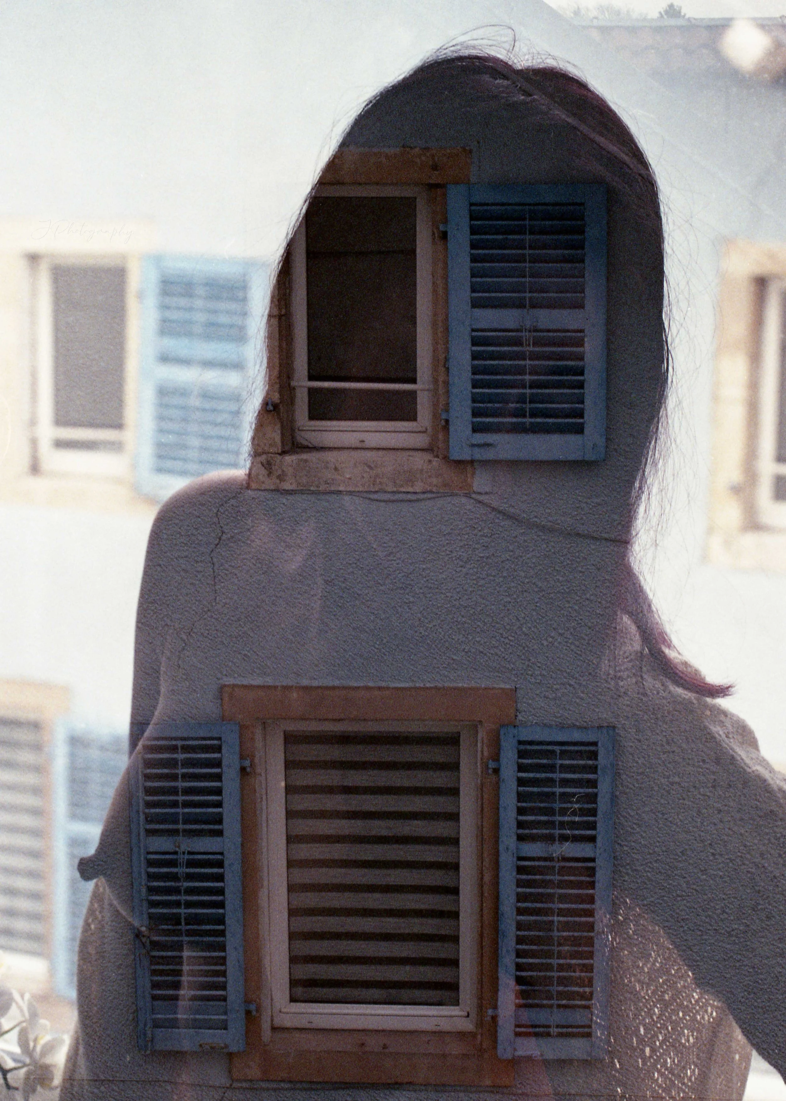 Double exposition photograph avec une silhouette de femme et deux fenêtres avec volets bleus.