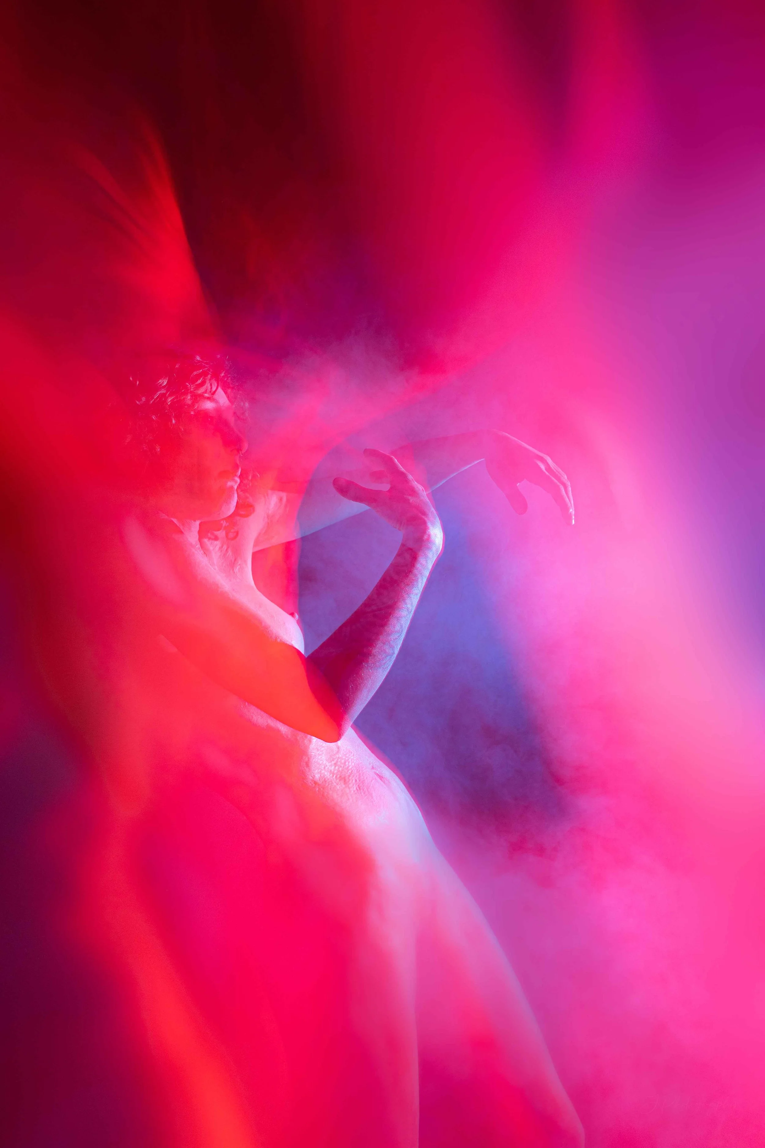 Une femme nue, en arrière-plan, enveloppée d'effets de lumière rose et violette, créant une atmosphère artistique et mystérieuse.