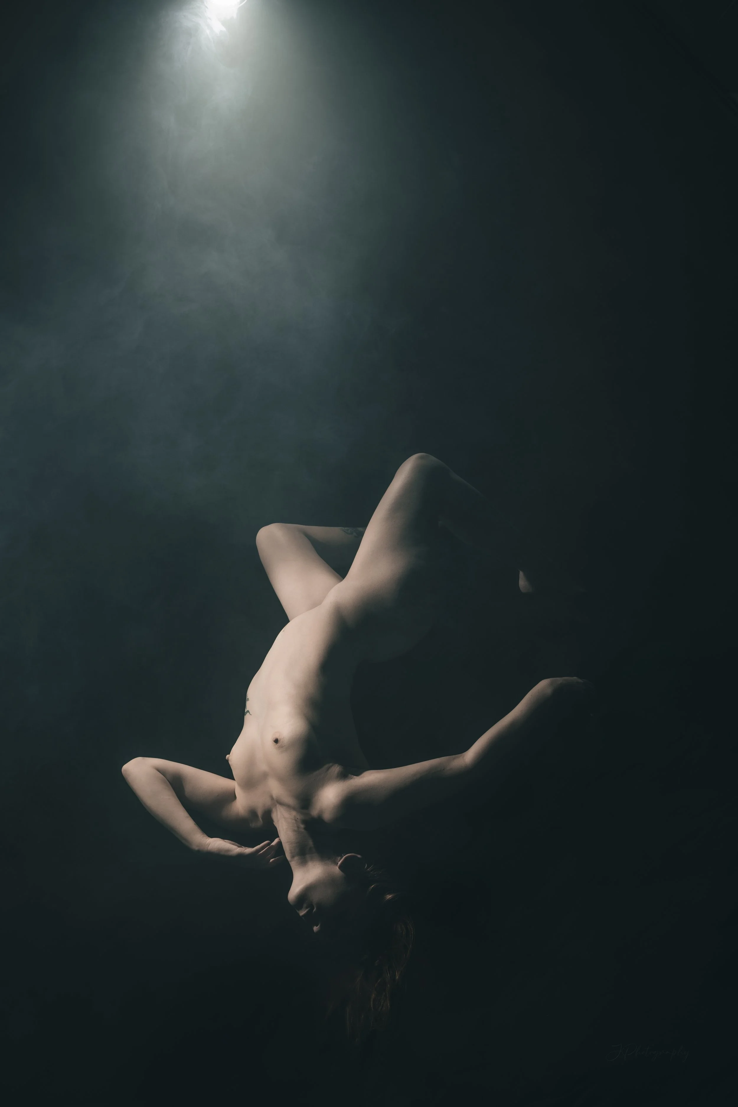 Technique de lévitation. Superbe composition de nu artistique, avec une ambiance mystérieuse, une lumière qui semble envelopper la modèle avec un brouillard blanc. 