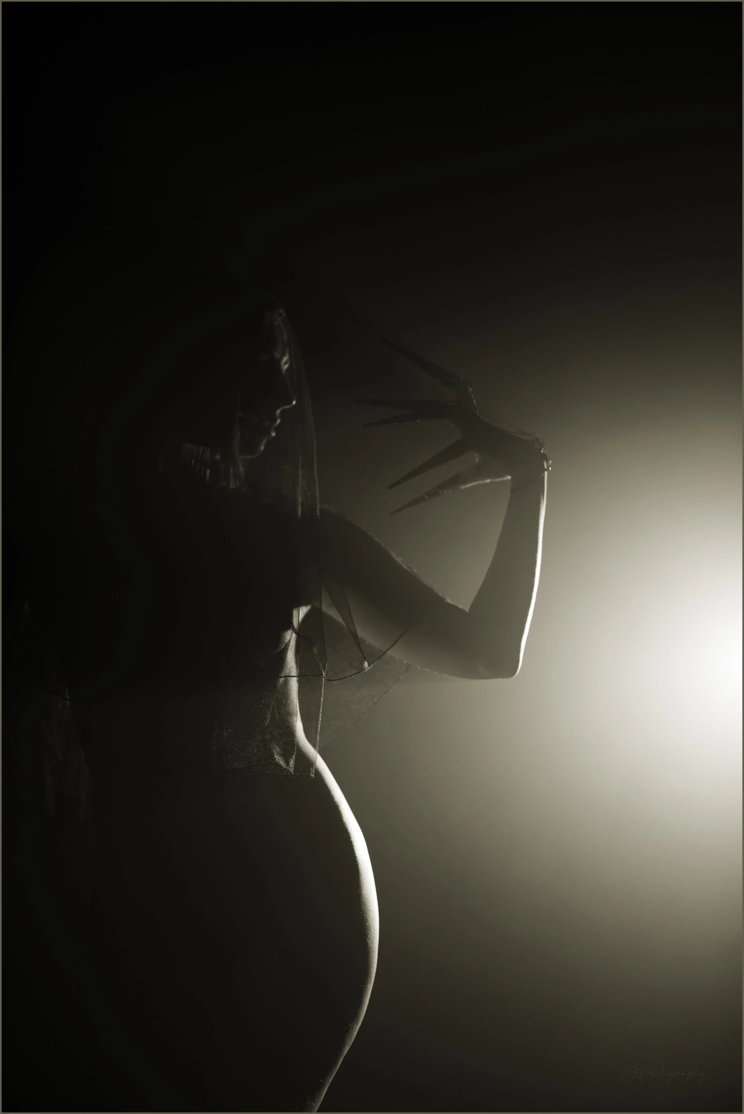 Photographie noir et blanc aux tons chauds pictorialiste et onirique représentant une femme nue, derrière de la brume, avec des doigts en forme de griffes. 