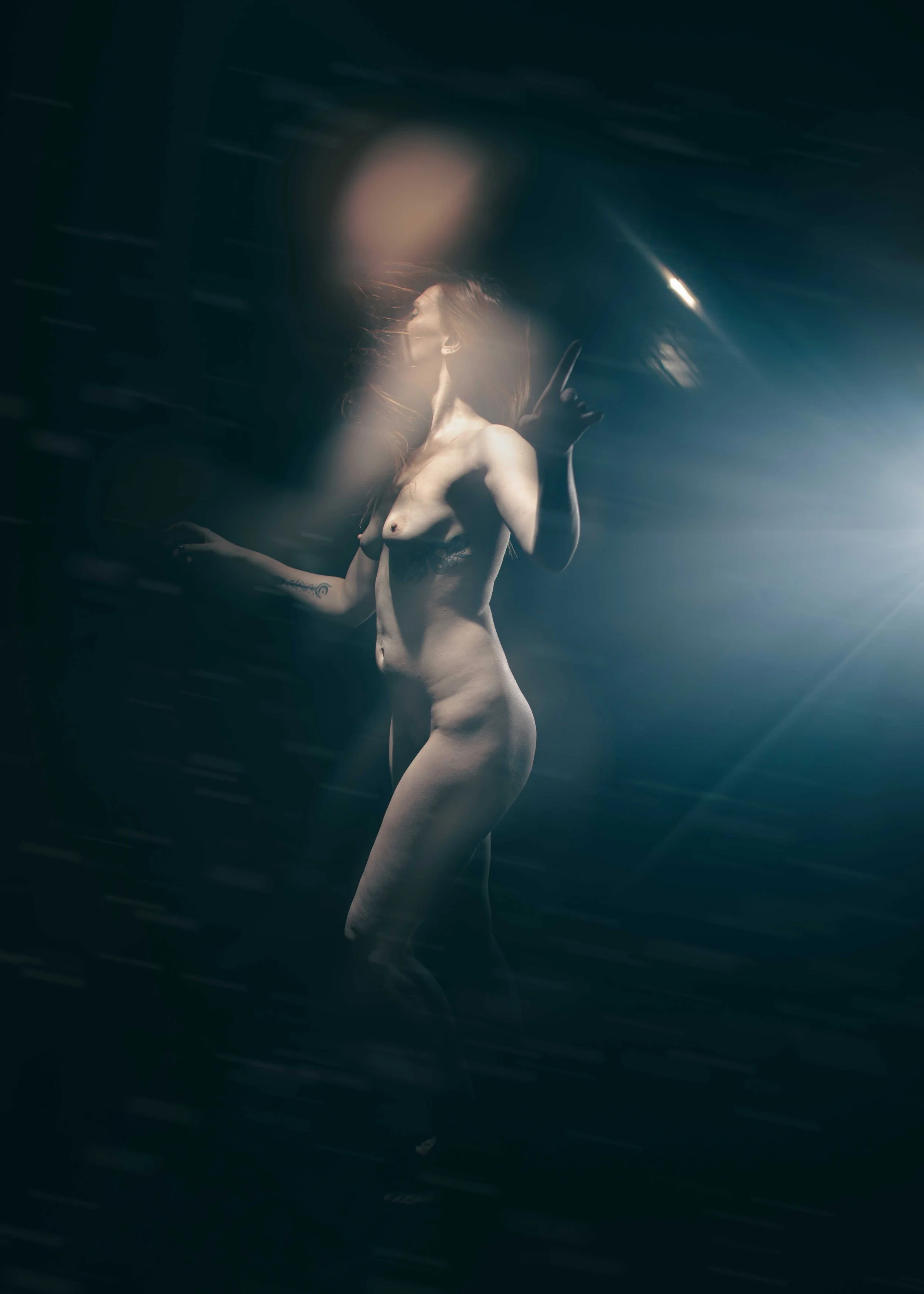 Femme nue dans une ambiance sombre et lumineuse, avec un effet flou et des lumières.