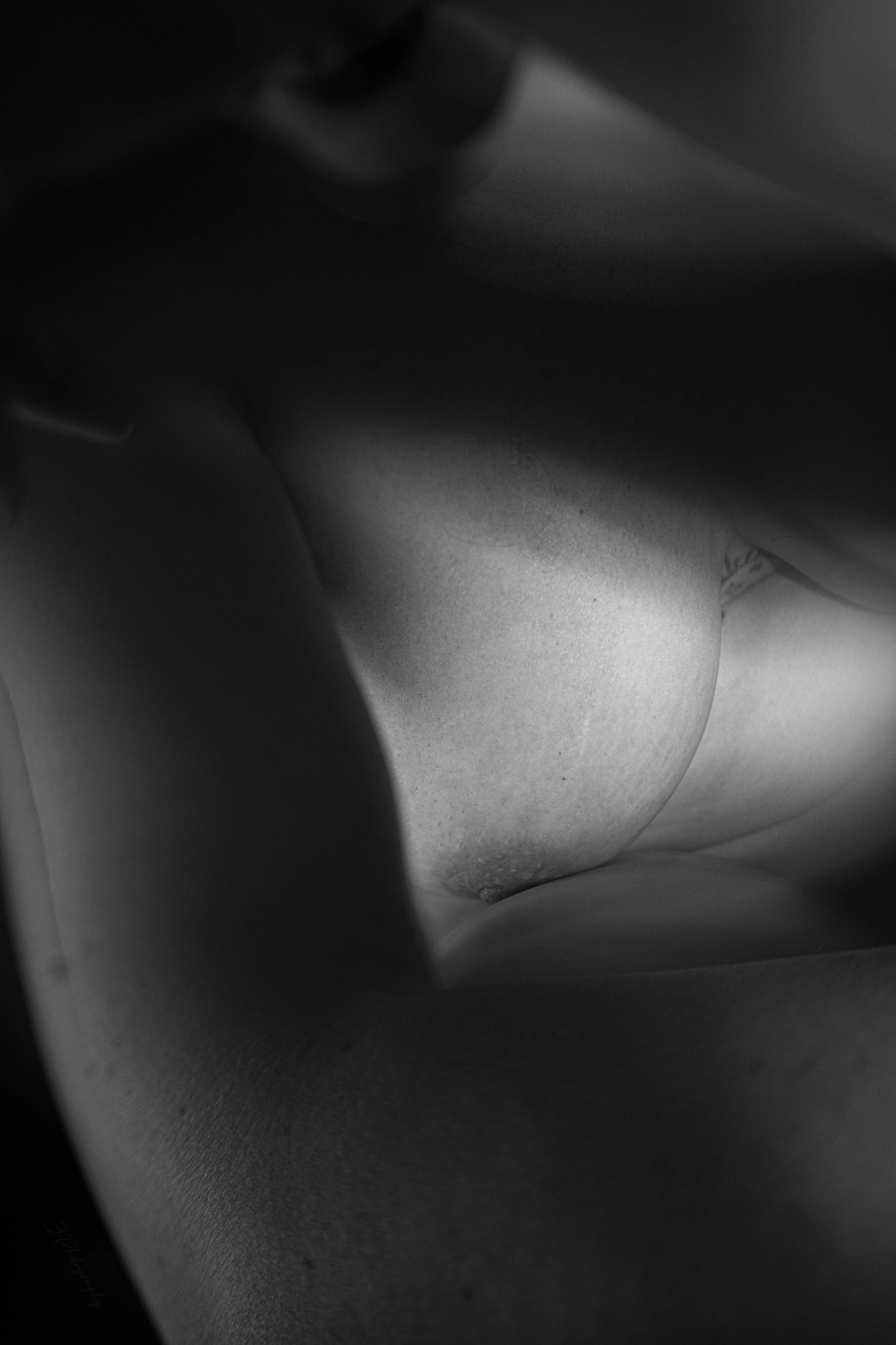 Détail en clair-obscur de la poitrine, de l'épaule et du bas du visage dune femme nue.